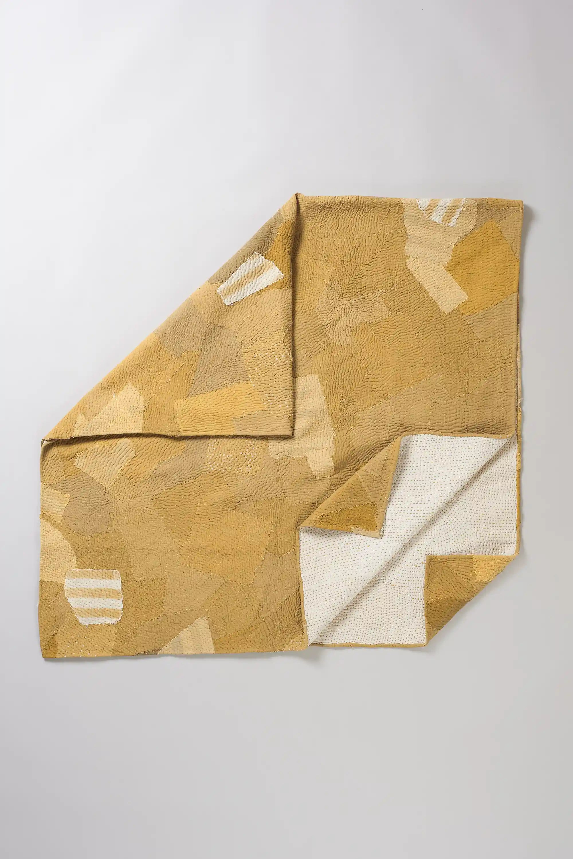 Folded yellow quilt with patchwork