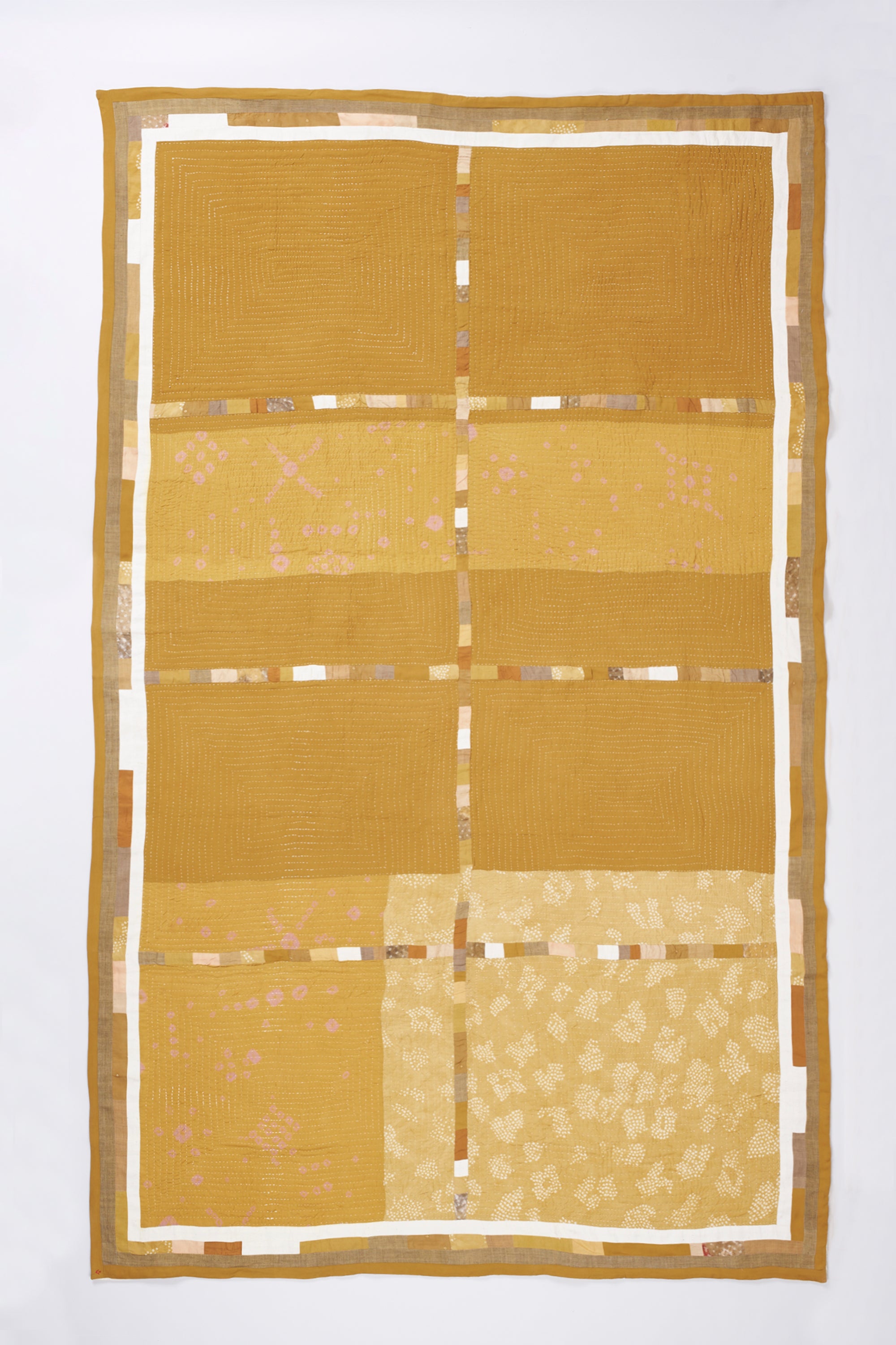 Ochere yellow quilt with gold and beige patterns on a white background