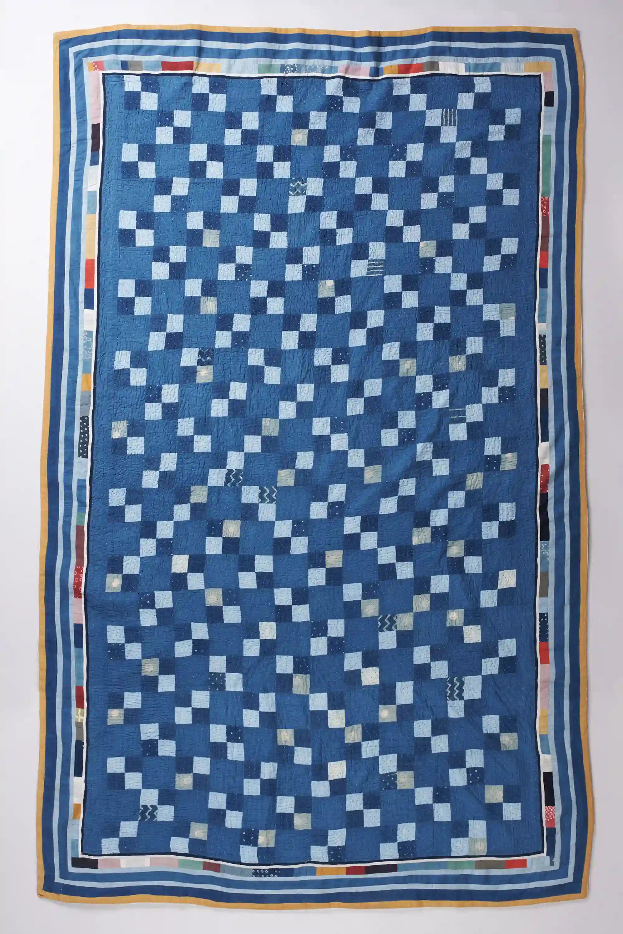 Quilt with a blue and white geometric pattern on a white background