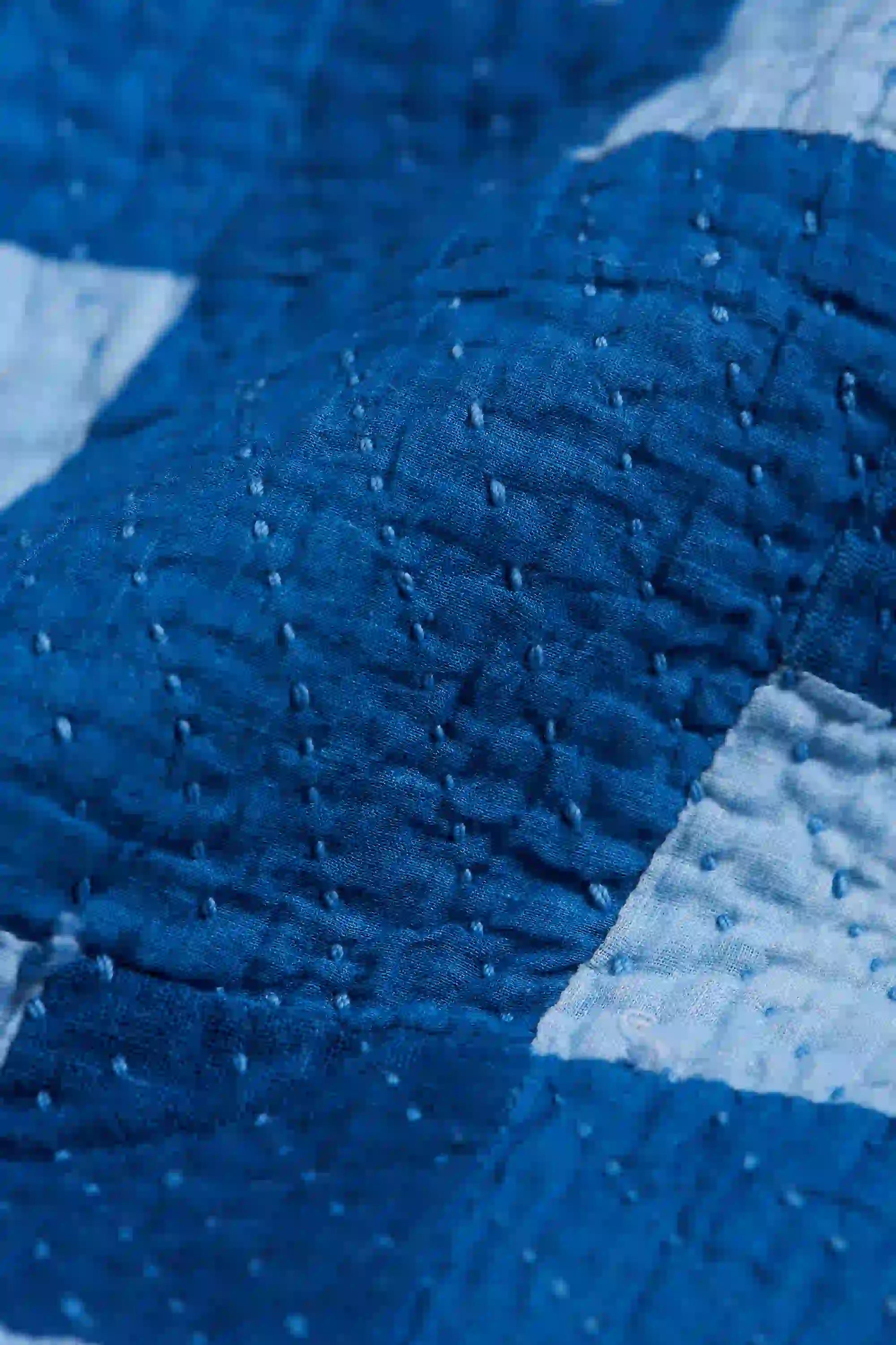 Close-up of a textured blue fabric with a quilted pattern