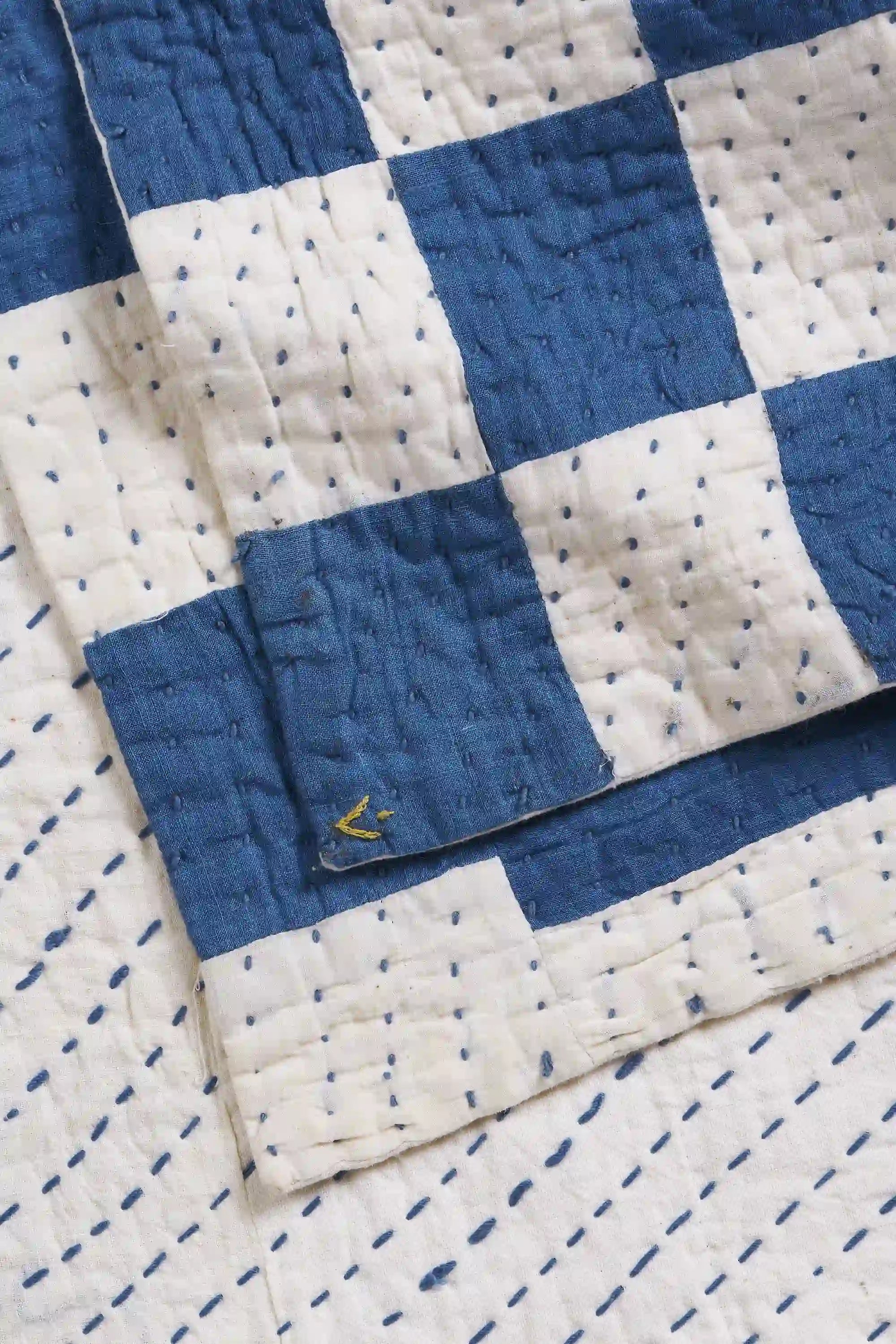Close-up of a blue and white quilt with a visible brand logo.