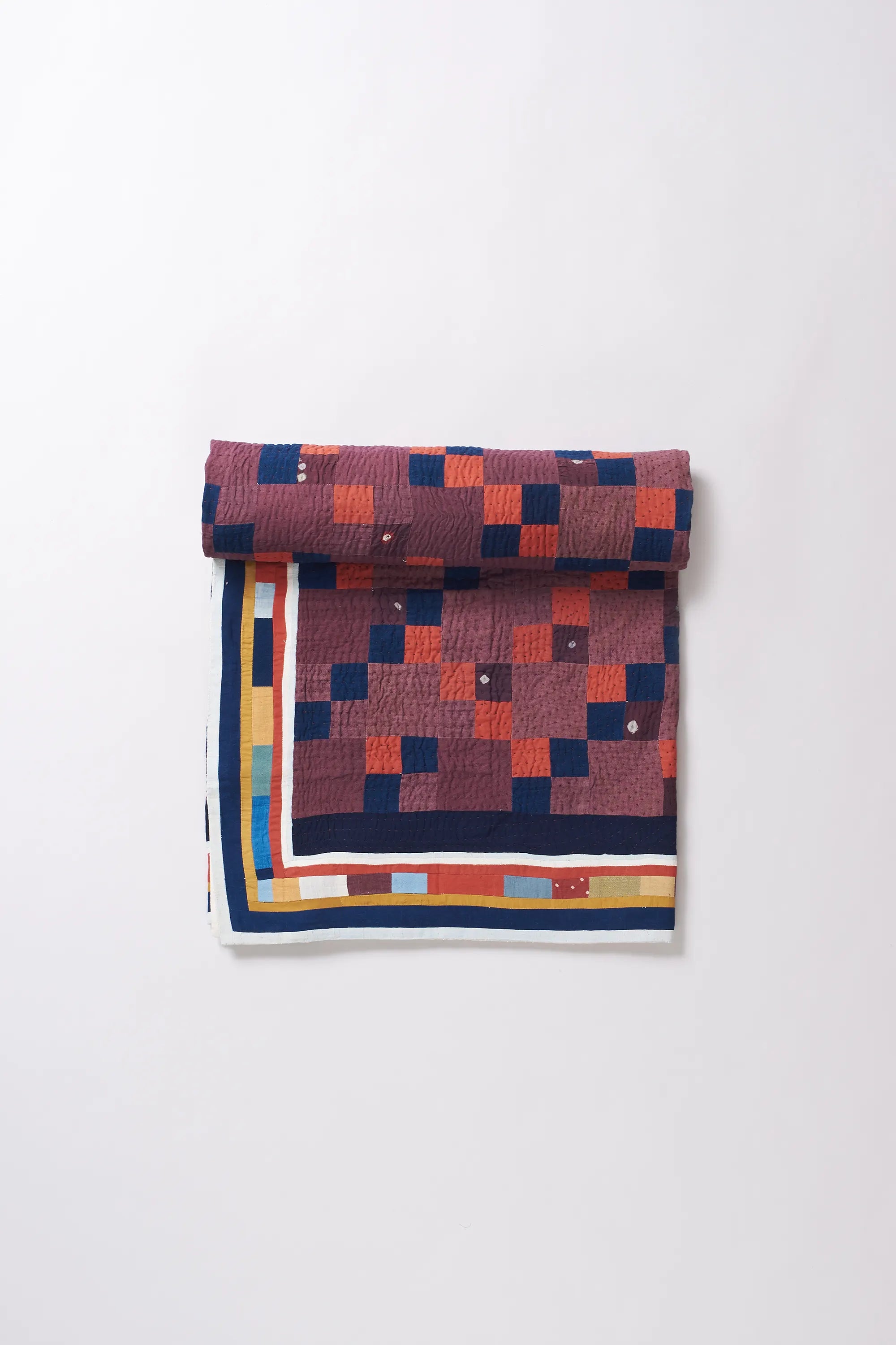 Colorful patterned quilt roll on a white background