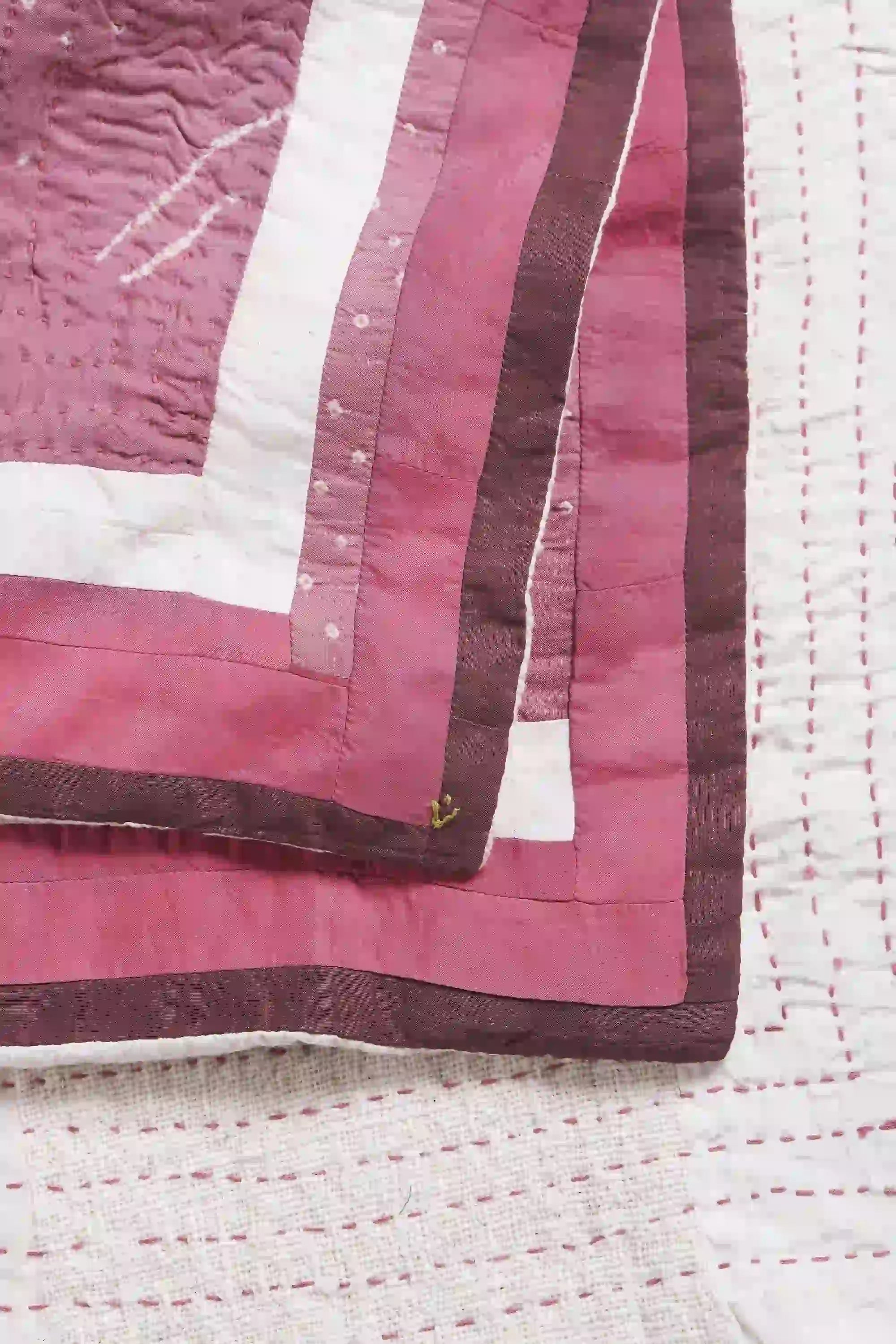 Close-up of a quilt with pink and white stripes on a textured surface