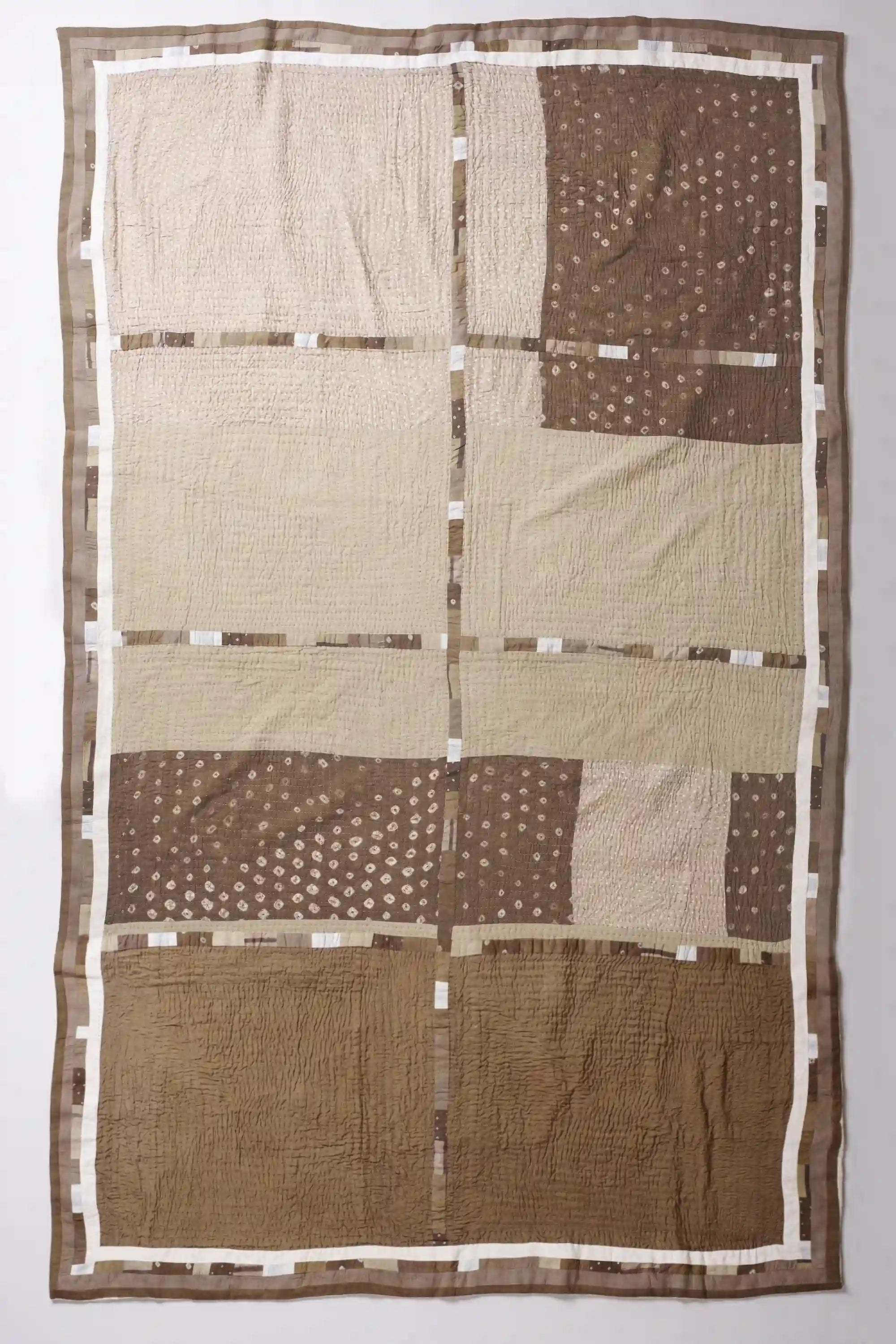 Patchwork quilt with brown and beige squares on a white background