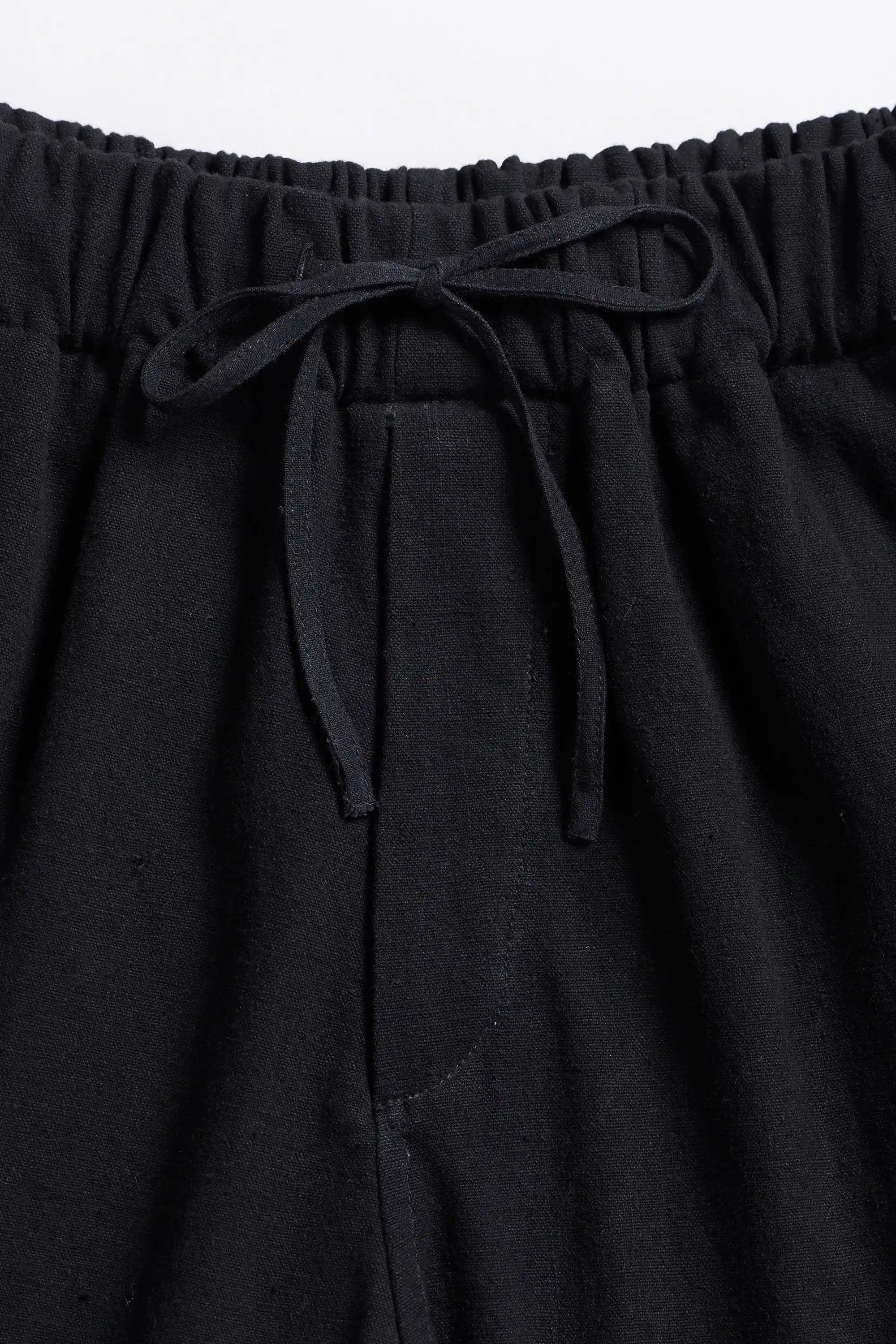 Black pants with drawstring waist on a light grey background