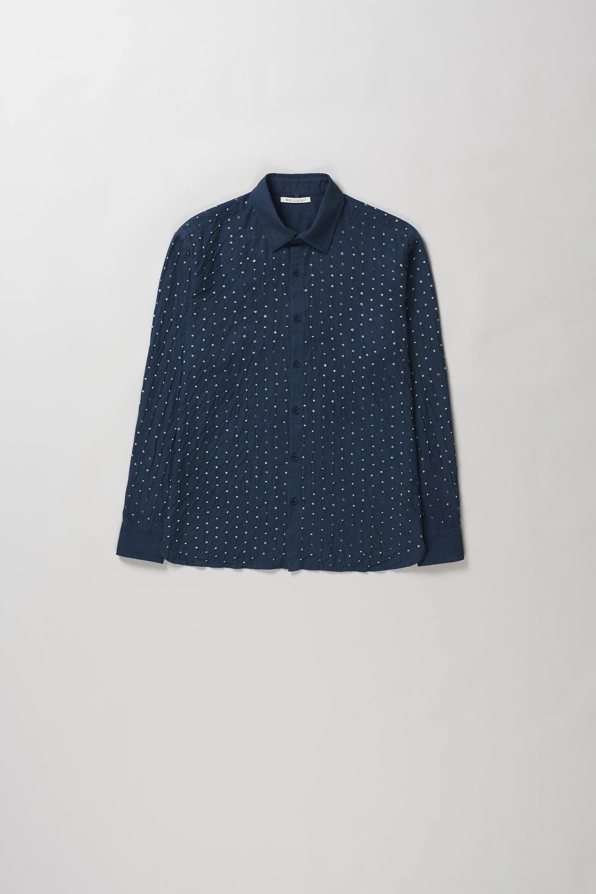 A space blue long-sleeve button-up shirt with a fine white dotted pattern, laid flat against a light grey background.
