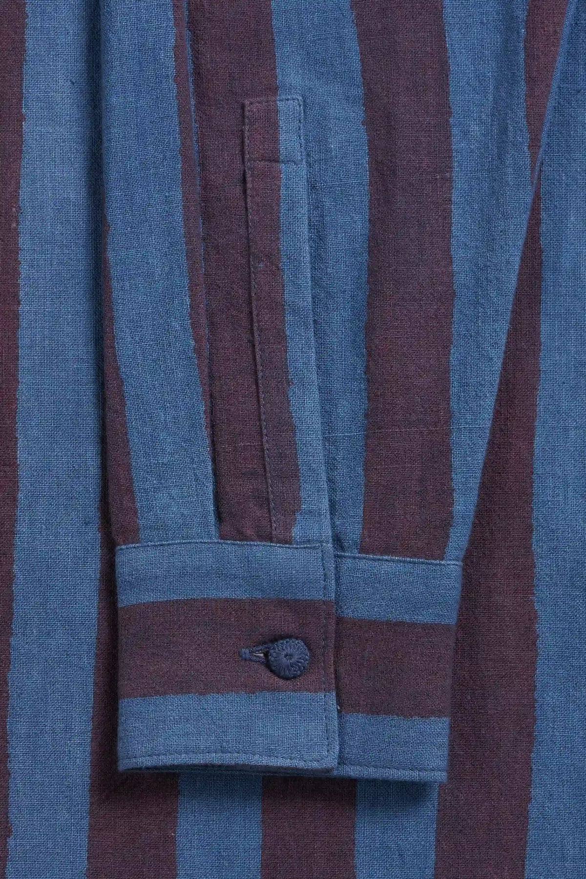 Close-up of a striped garment fabric with alternating muted blue and dark burgundy vertical stripes.