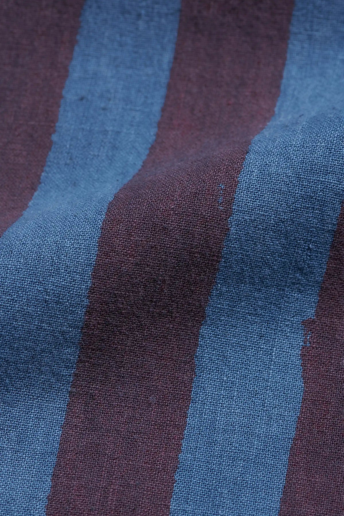 Close-up of a striped woven fabric with alternating vertical bands of muted blue and dark burgundy.