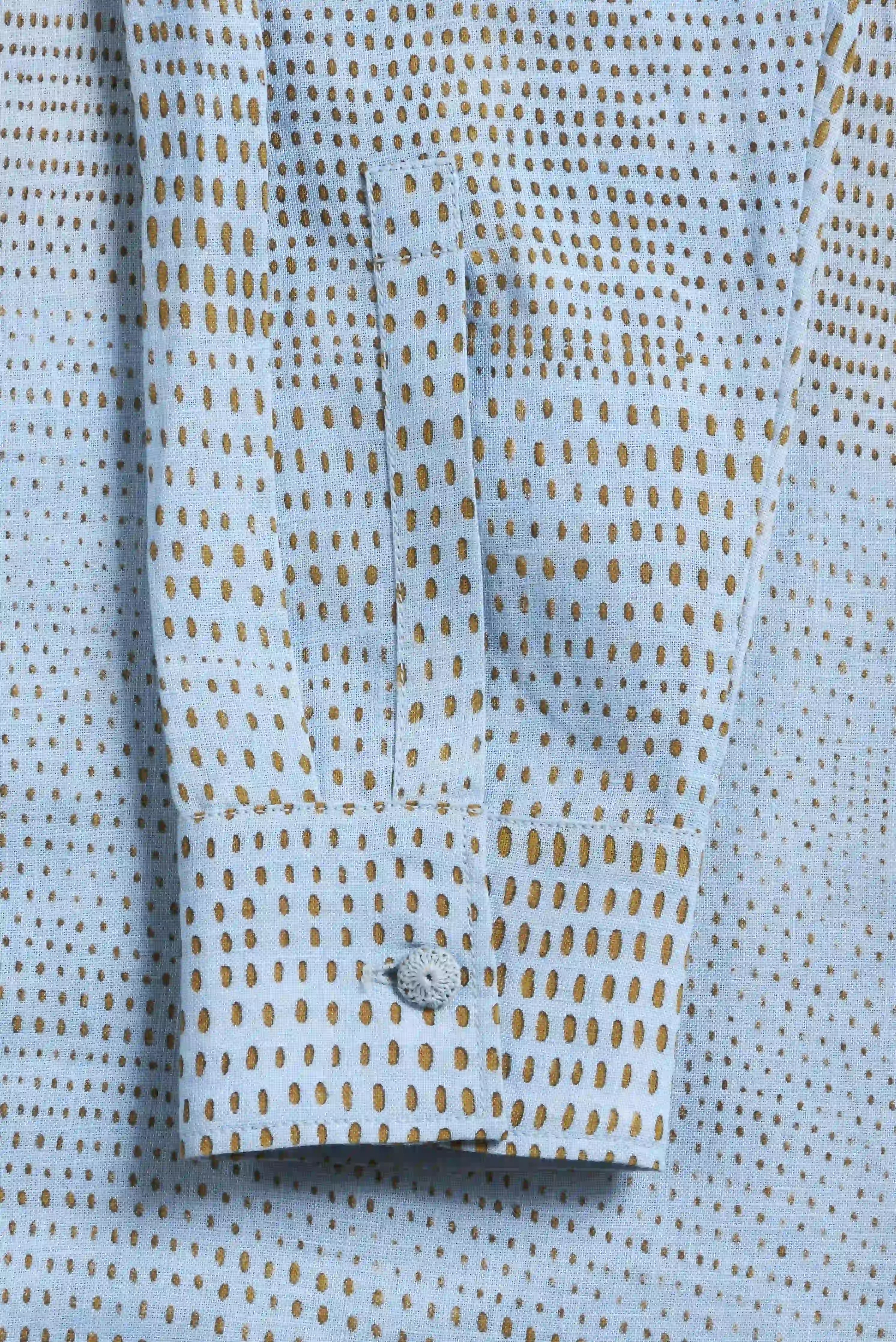 Close-up of a light blue shirt with gold pattern and button