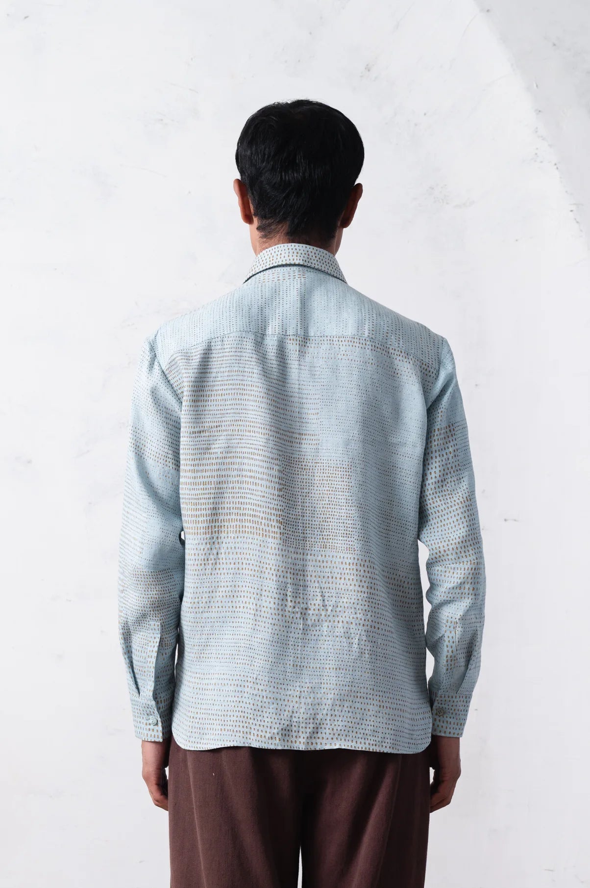 Back shot of a person wearing a light blue checkered shirt against a white background