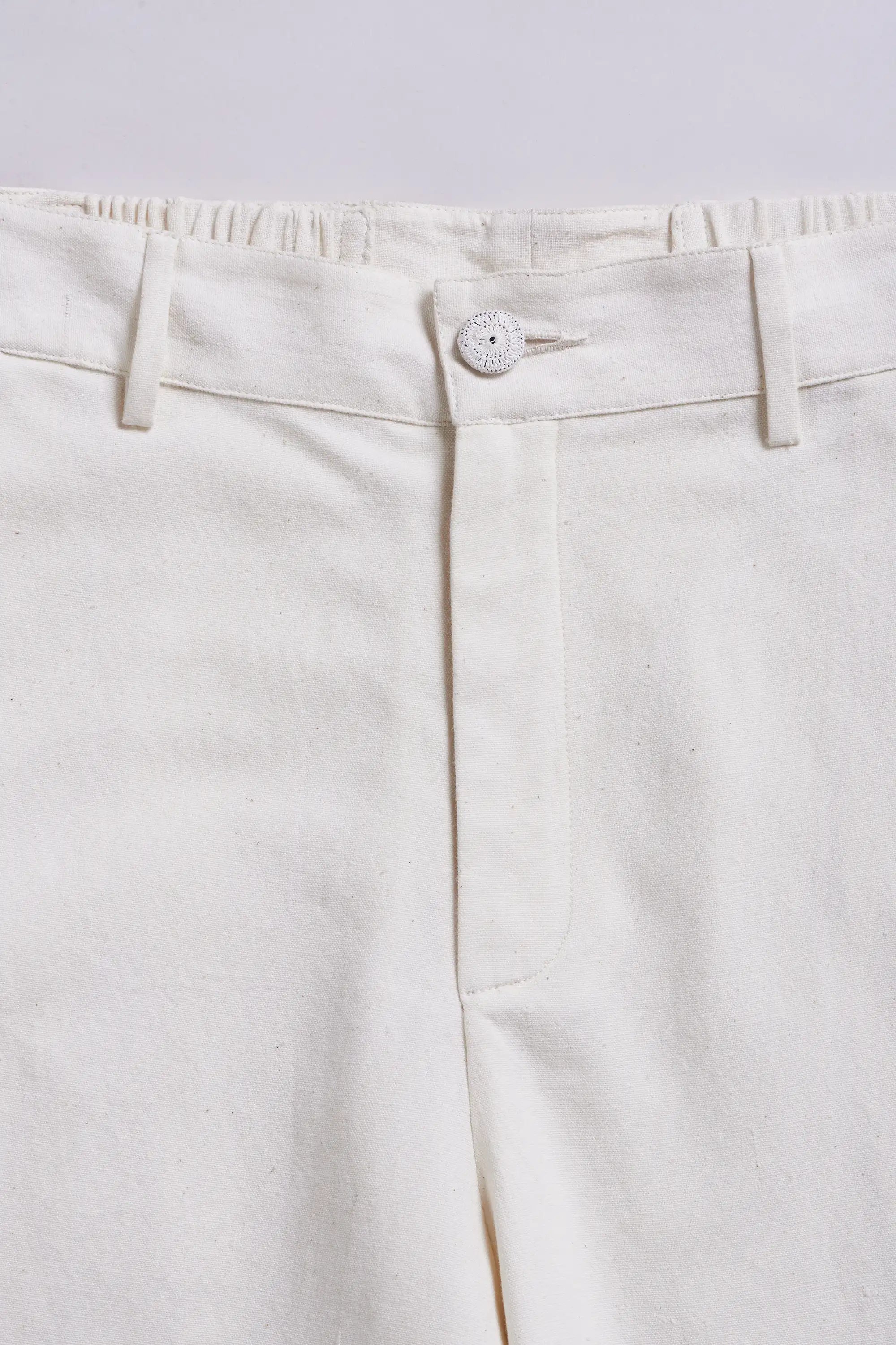 Close-up of a white pants with a button on a light grey background