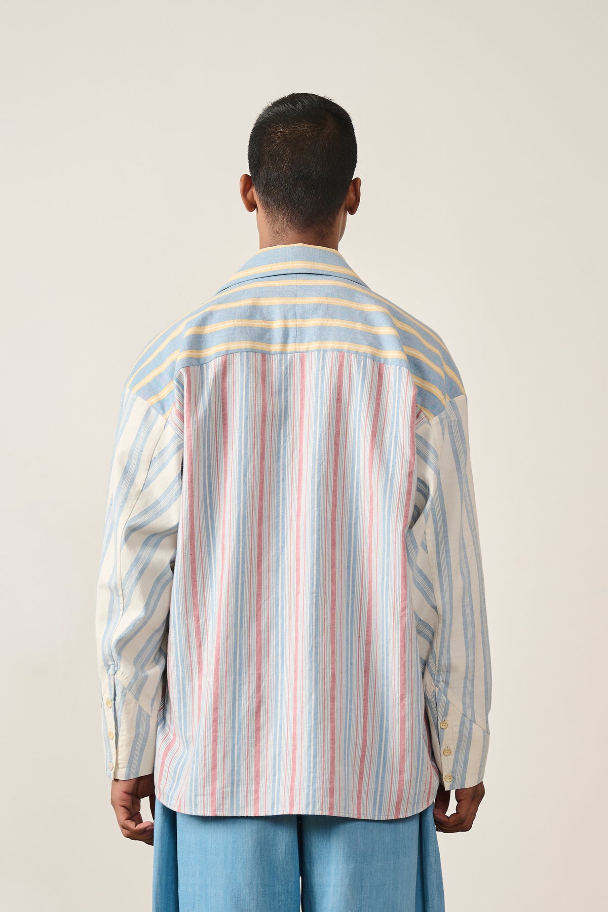 A back shot of a man wearing multi colour shirt