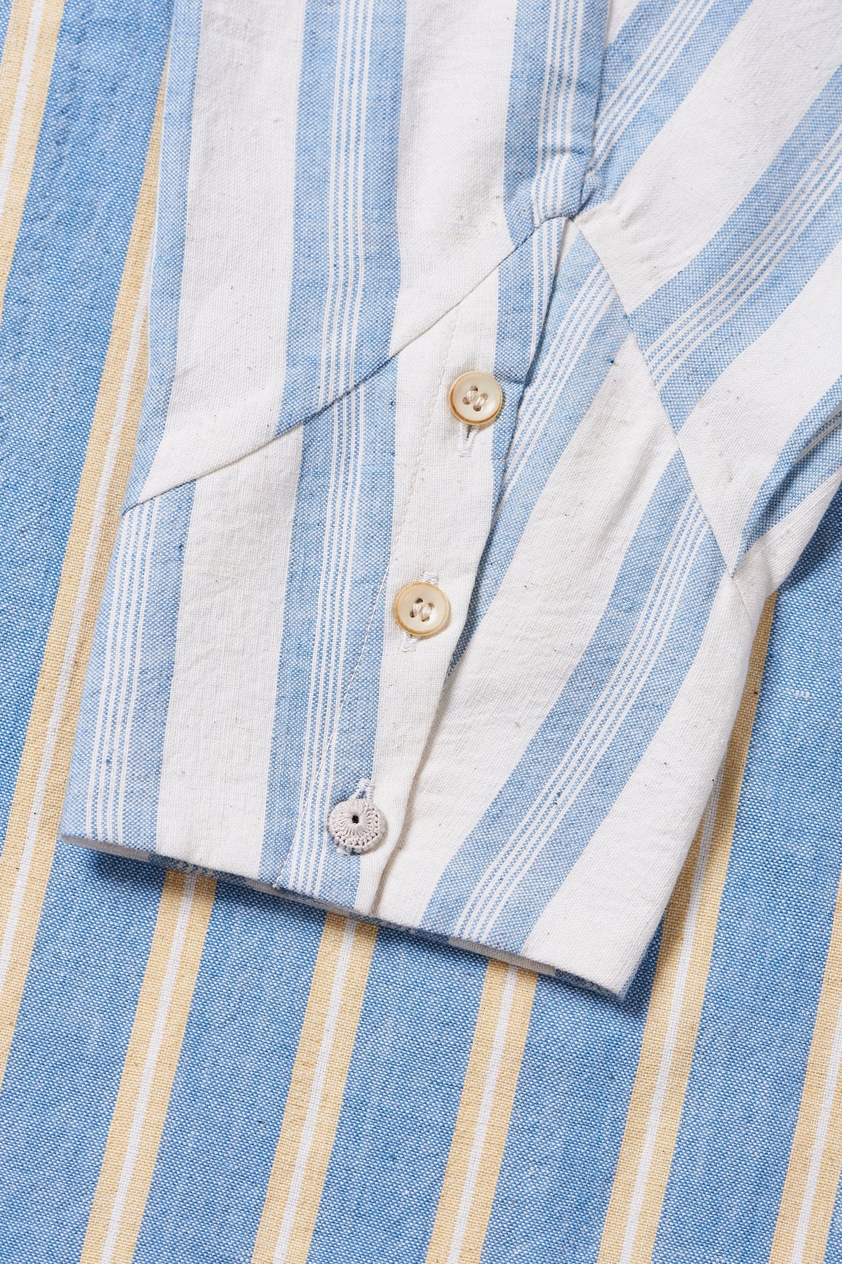 Close-up of a blue and white striped shirt with buttons and sleeve