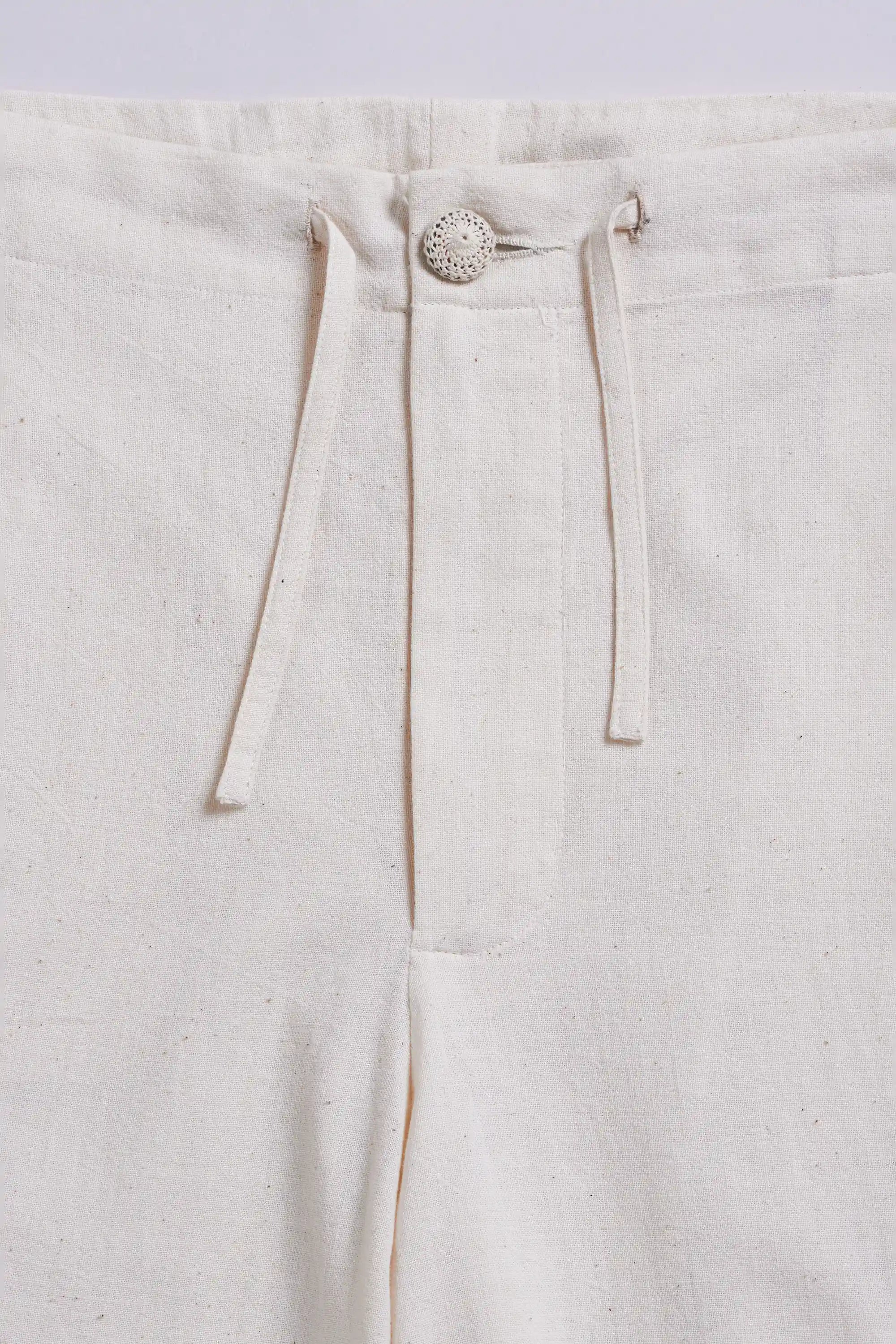 Close-up of pants with a button and drawstring on a light grey background