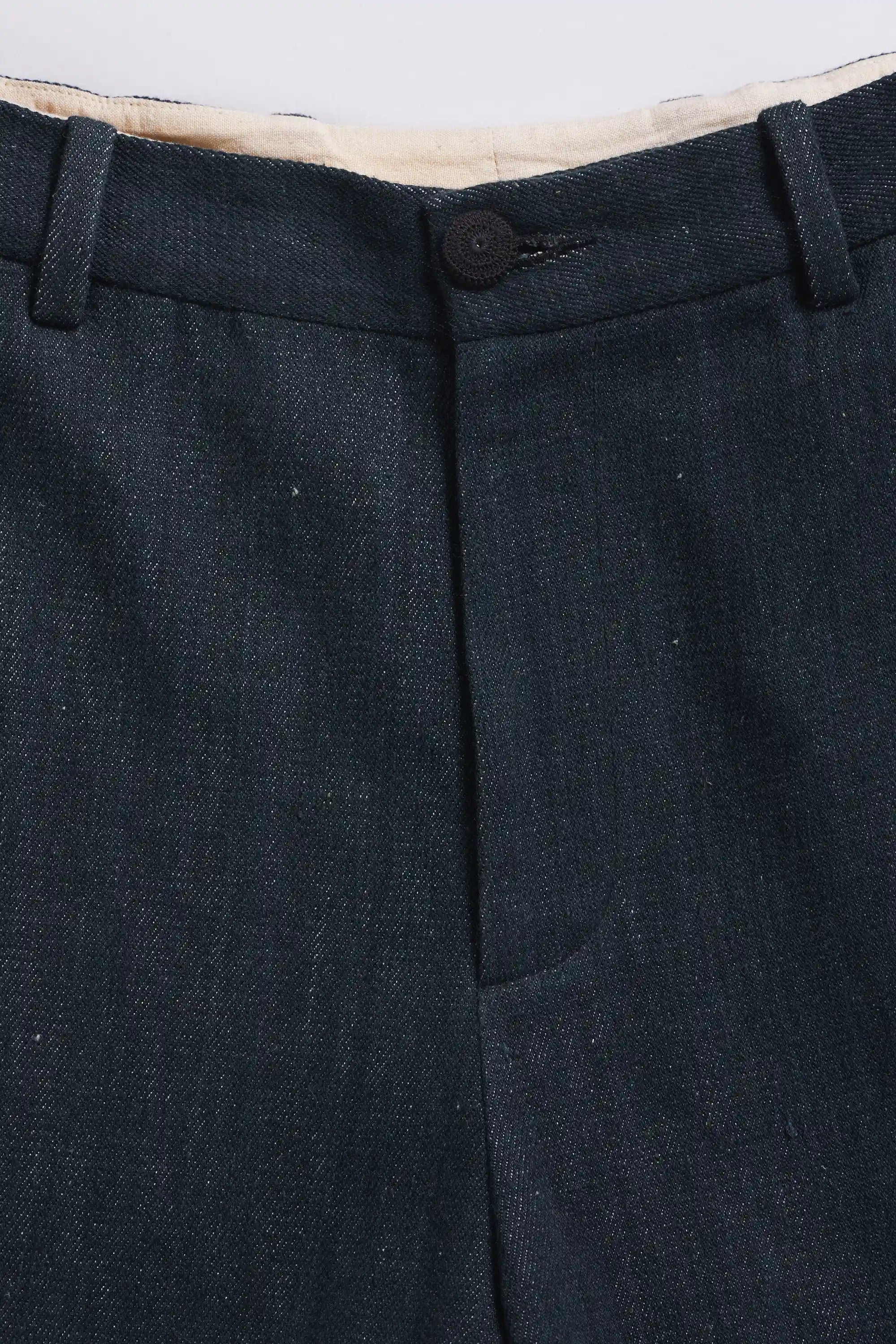 Midnight indigo pants with a button on a light grey background
