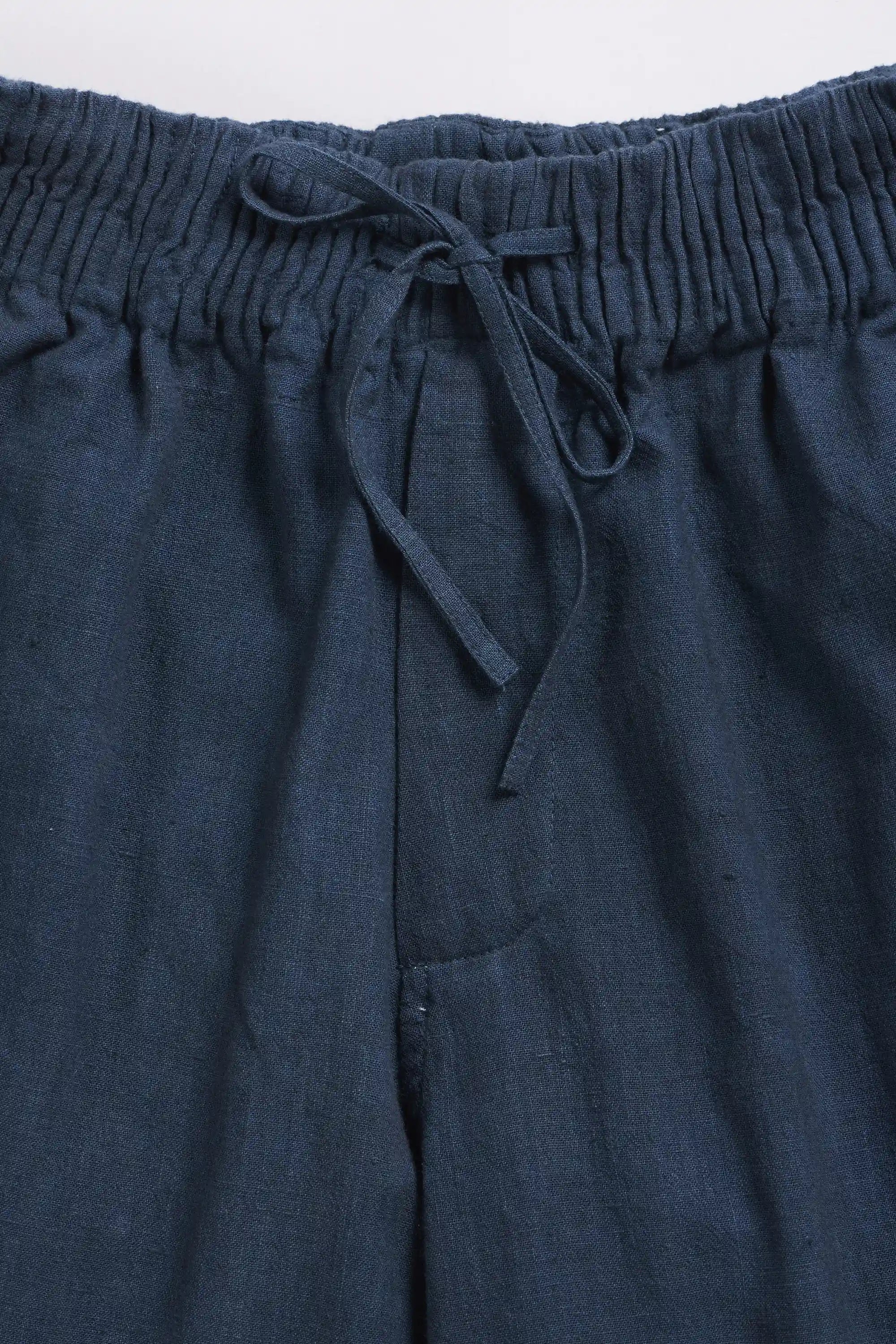 Close-up of dark blue pants with a drawstring waistband on a light grey background