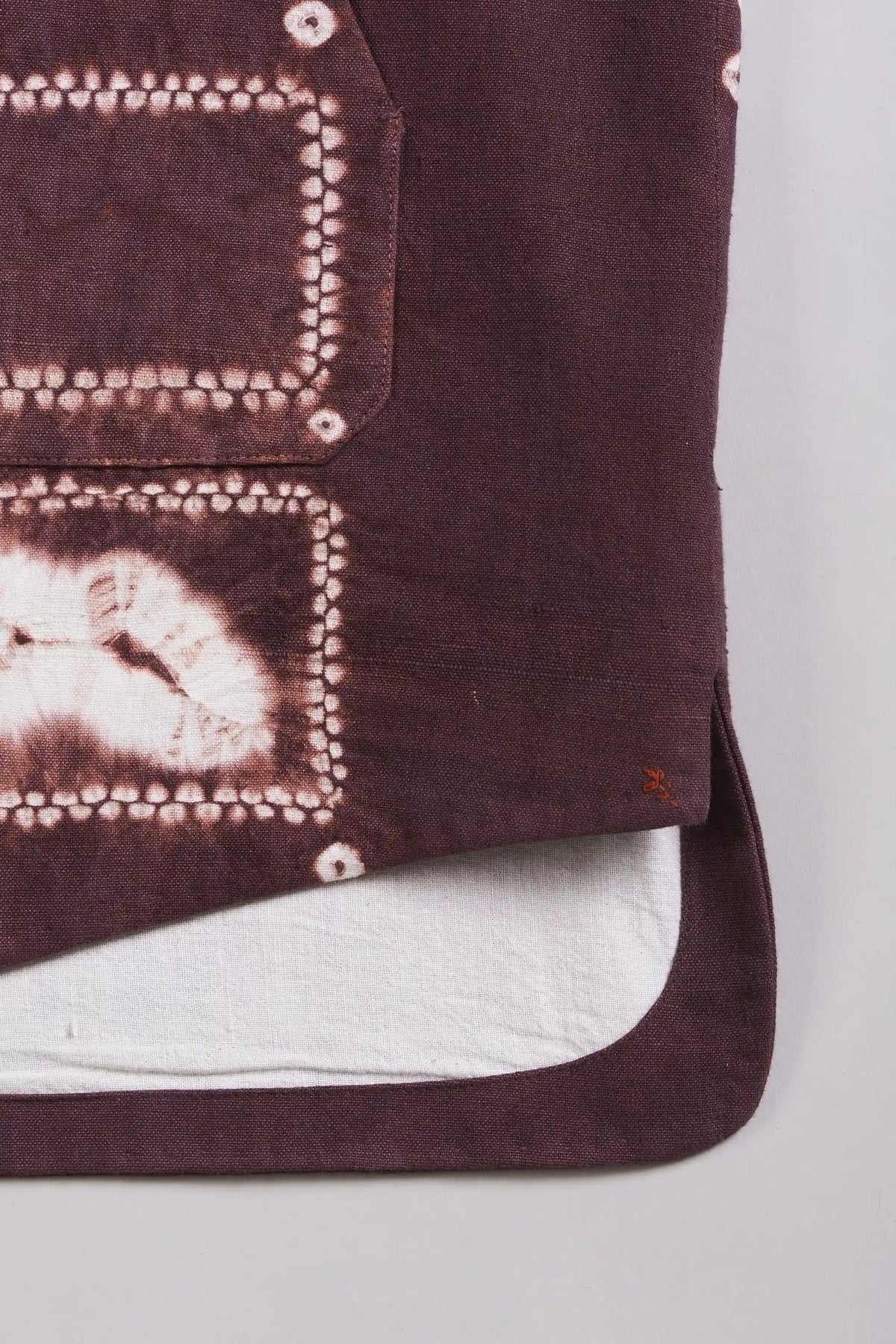 A close-up of a purple fabric textile with white tie-dye shibori with pehchan.