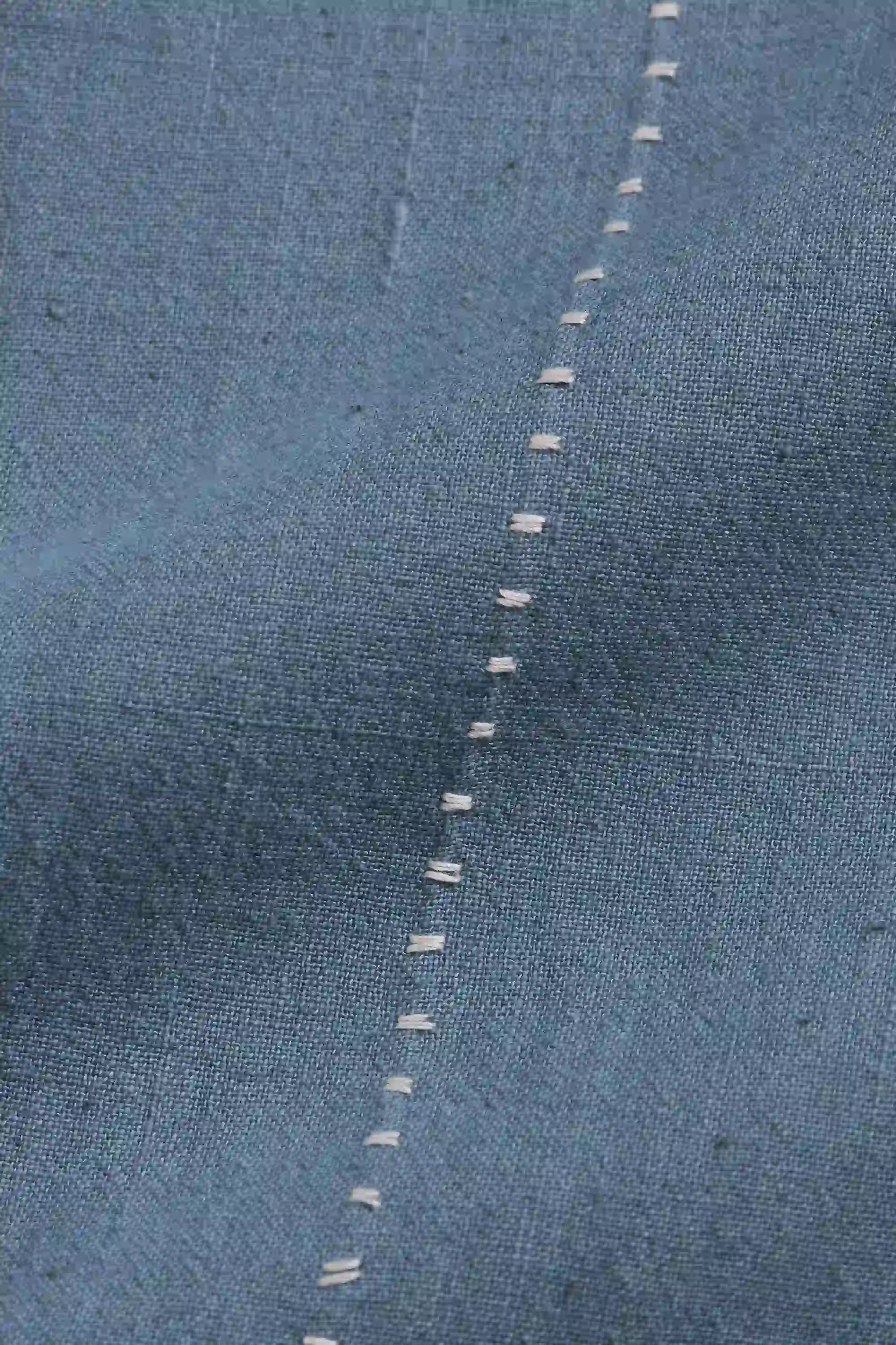 Close-up of a blue denim fabric with a visible seam.