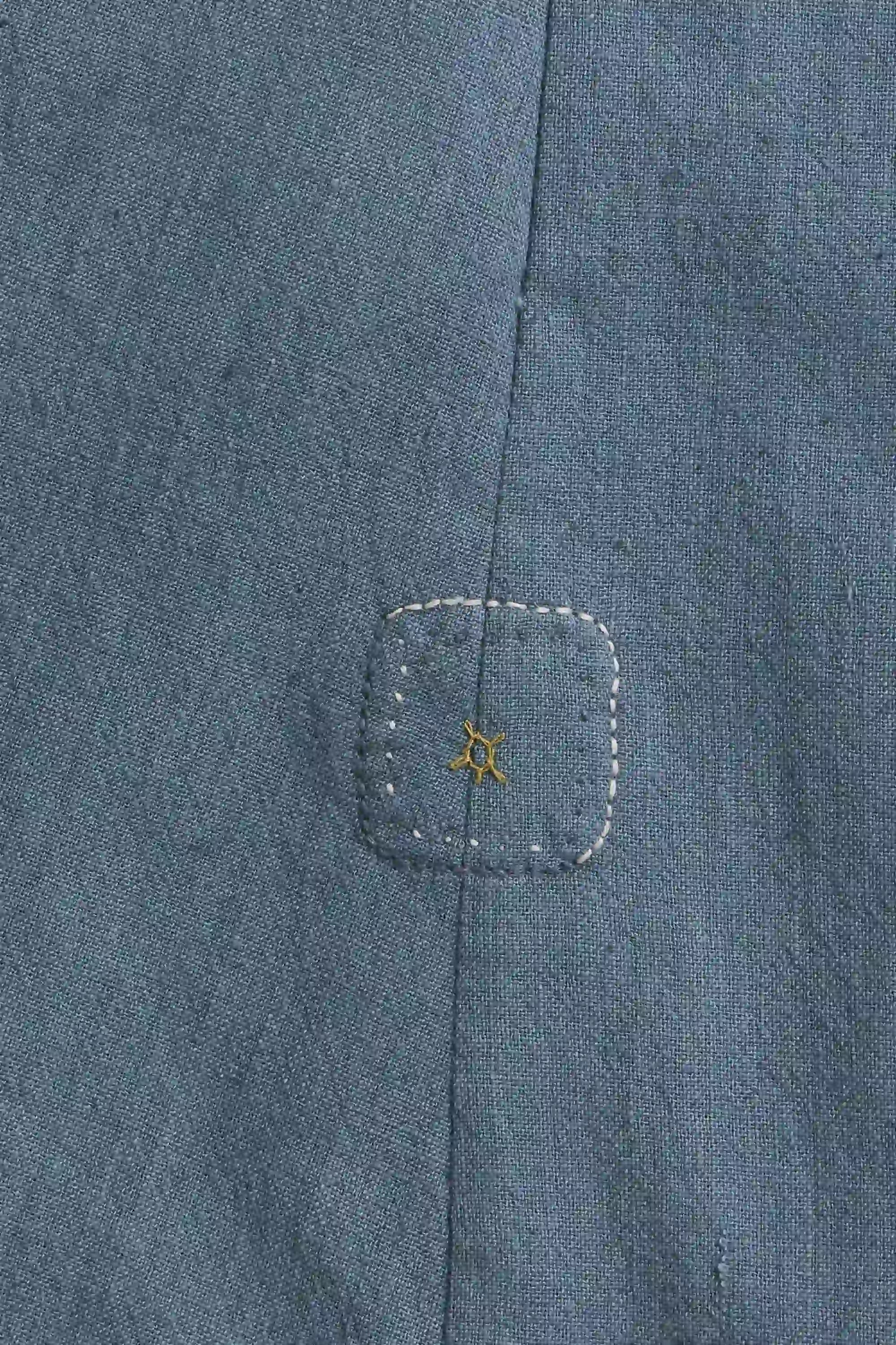 Close-up of a blue denim pocket with a small embroidered design.