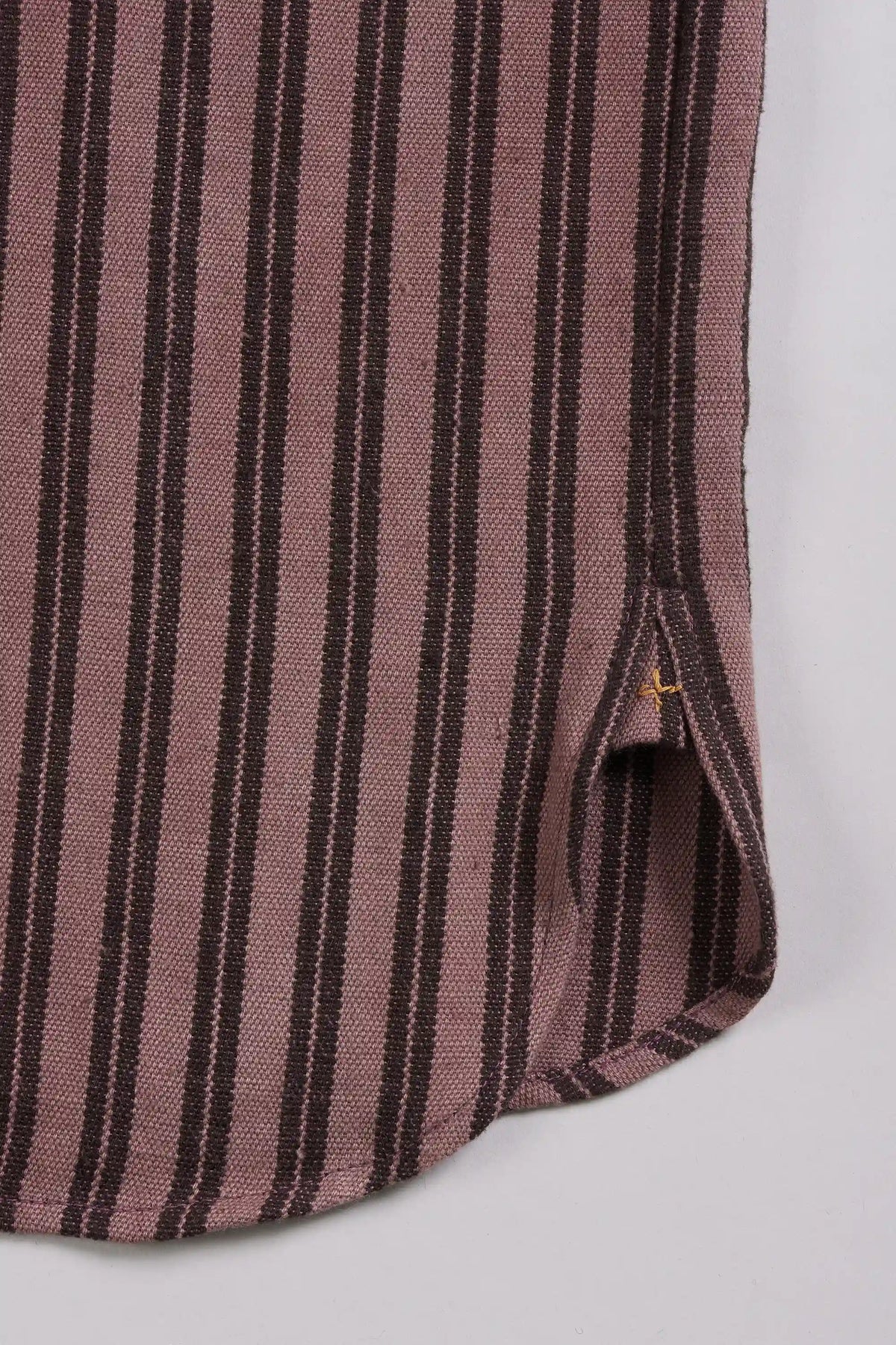 Close-up of a striped textile with vertical dark brown and dusty rose stripes on a light grey background.