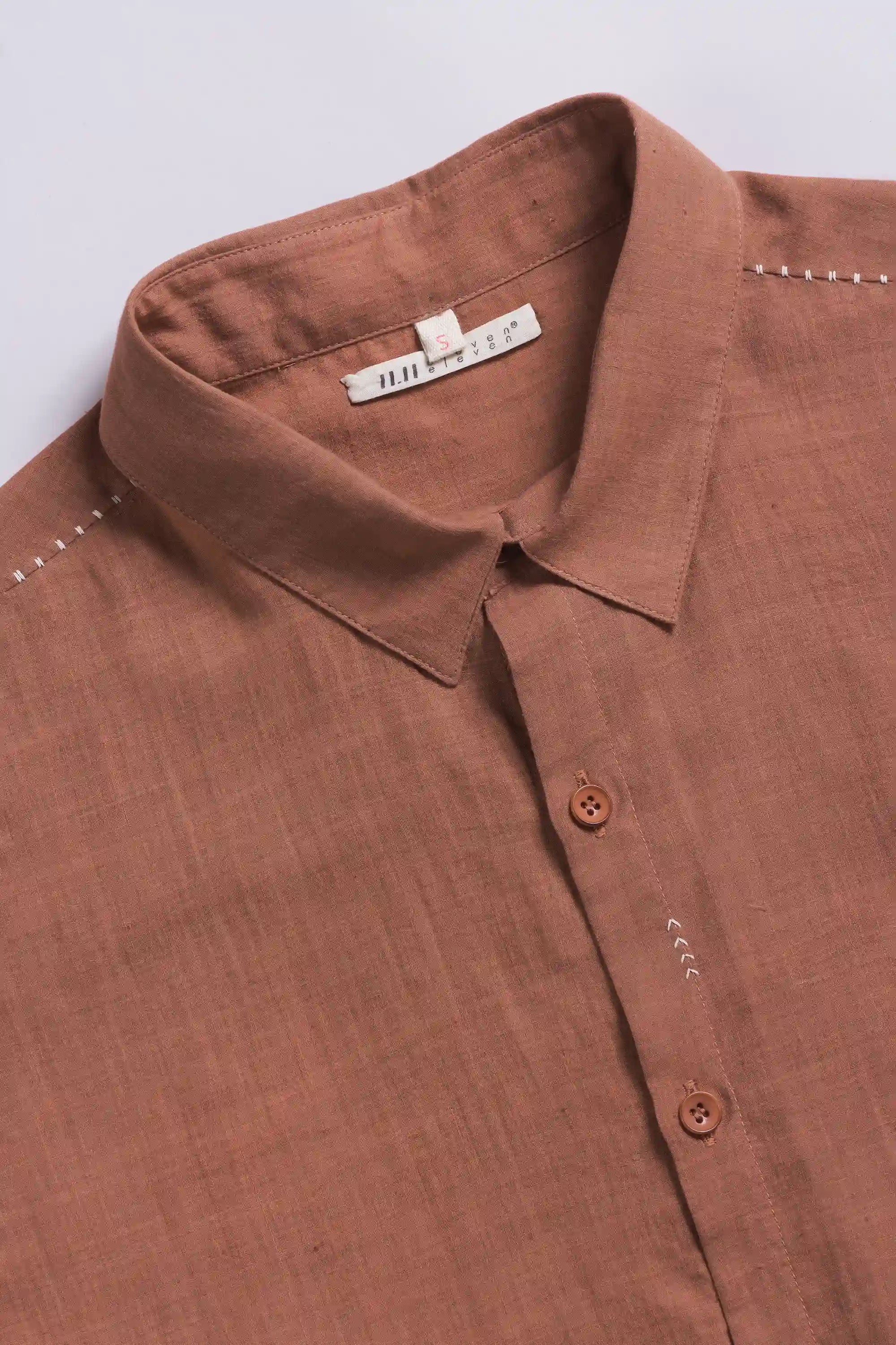 Close-up of a orange rust shirt with a collar and buttons on a light grey back ground