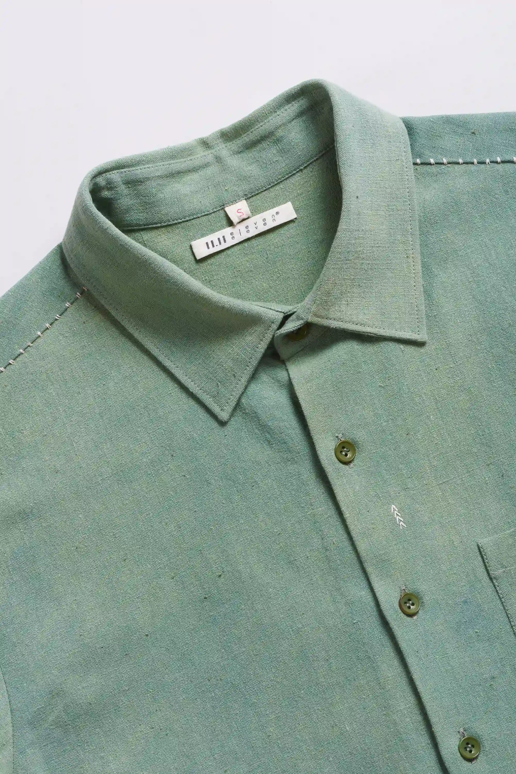 Green shirt with collar and brand label on a light grey background