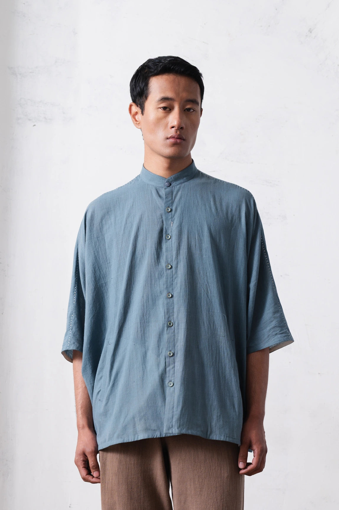Man wearing a light blue shirt with a light grey background
