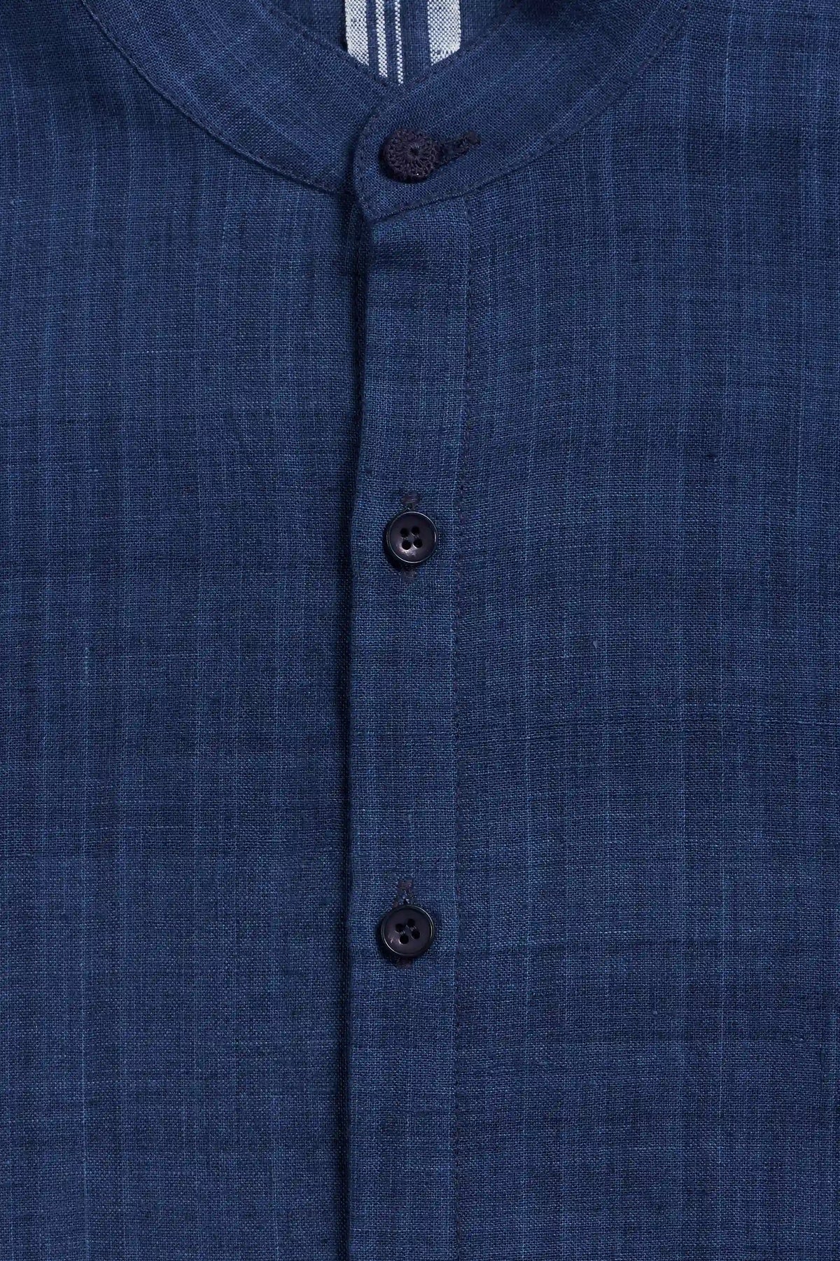 Close-up of a indigo textured fabric garment with a mandarin collar and three dark buttons down the front.