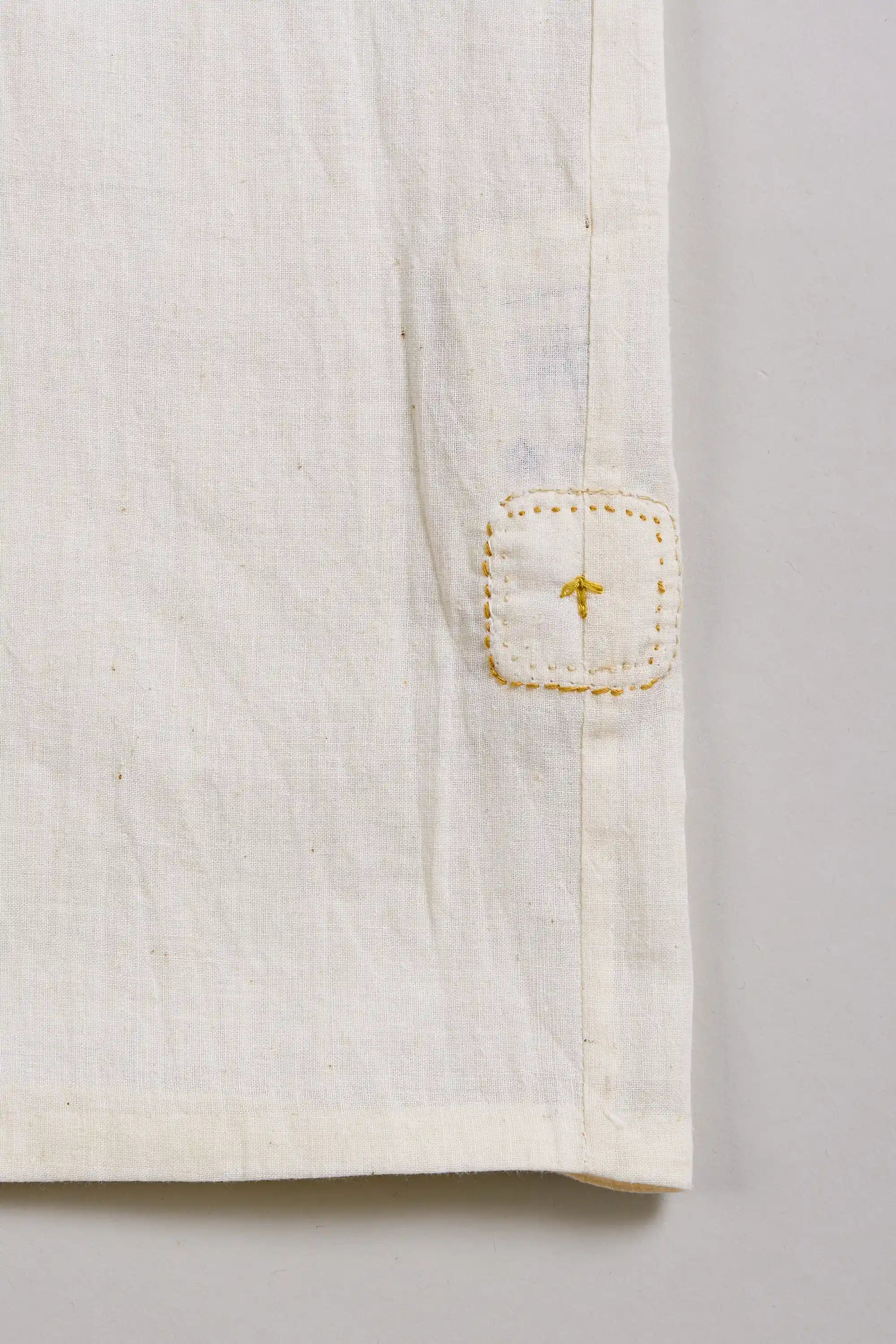 Close-up of a ecru shirt with a pehchanbox on a light grey background