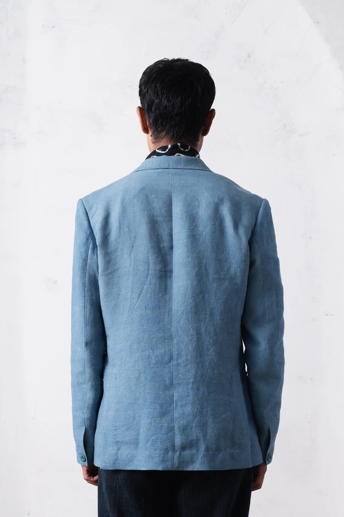 Back shot of a person wearing a powder blue jacket against a light grey background
