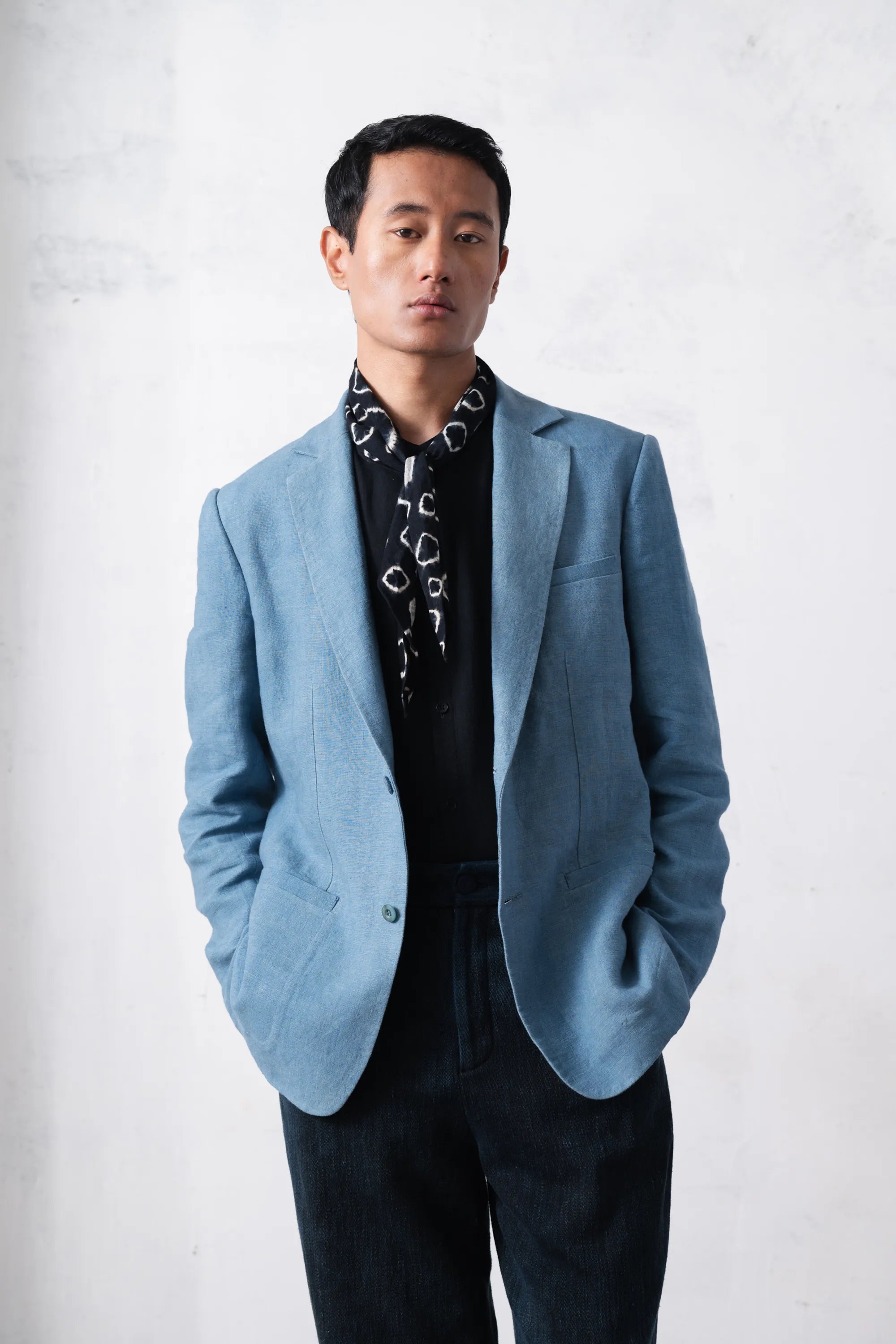 Man wearing a light blue jacket over a black t-shirt against a light grey background