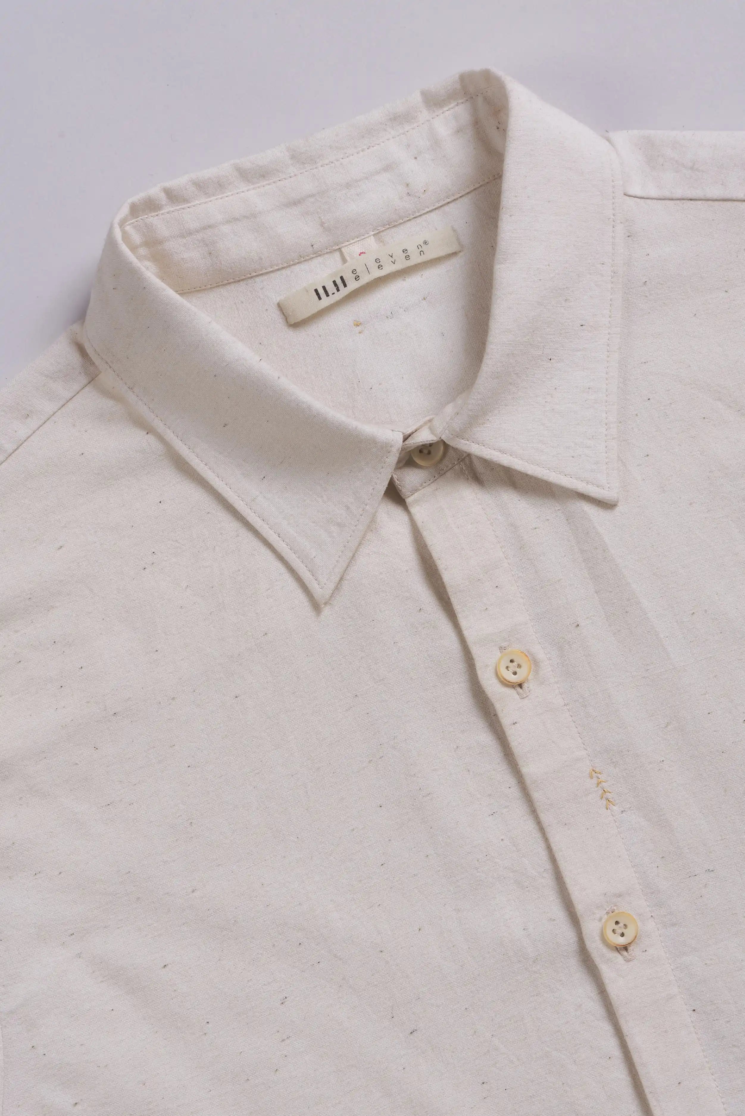Close-up of a shirt with a collar and buttons on a light grey background