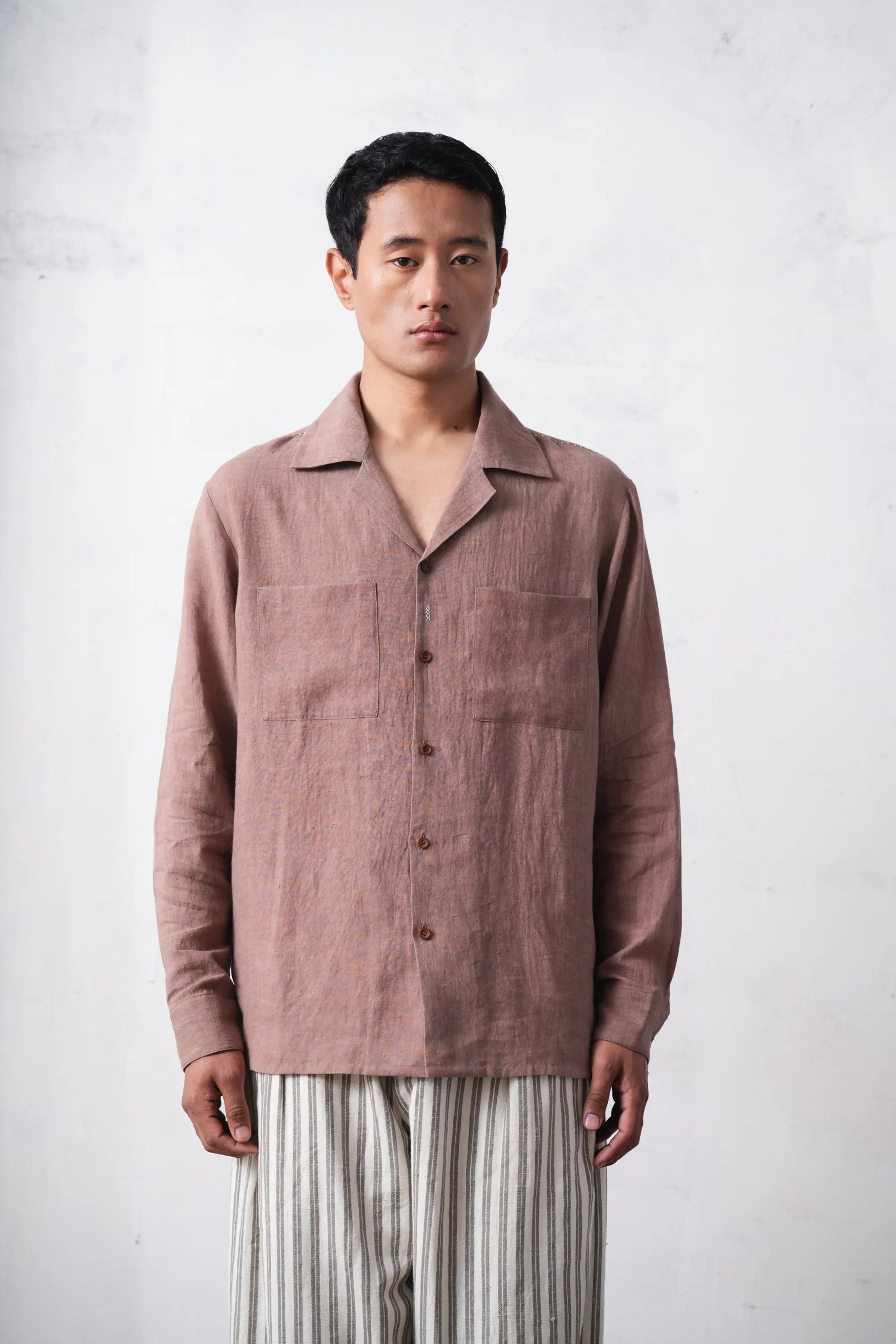 Man wearing a shirt and striped pants against a light grey background