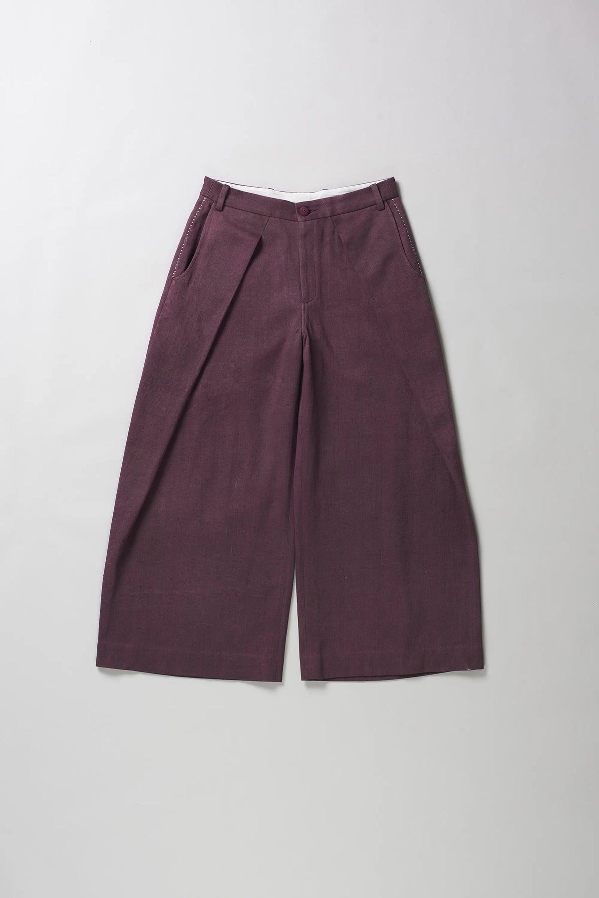 A pair of wide-leg trousers in a purple color, laid flat against a light grey background.