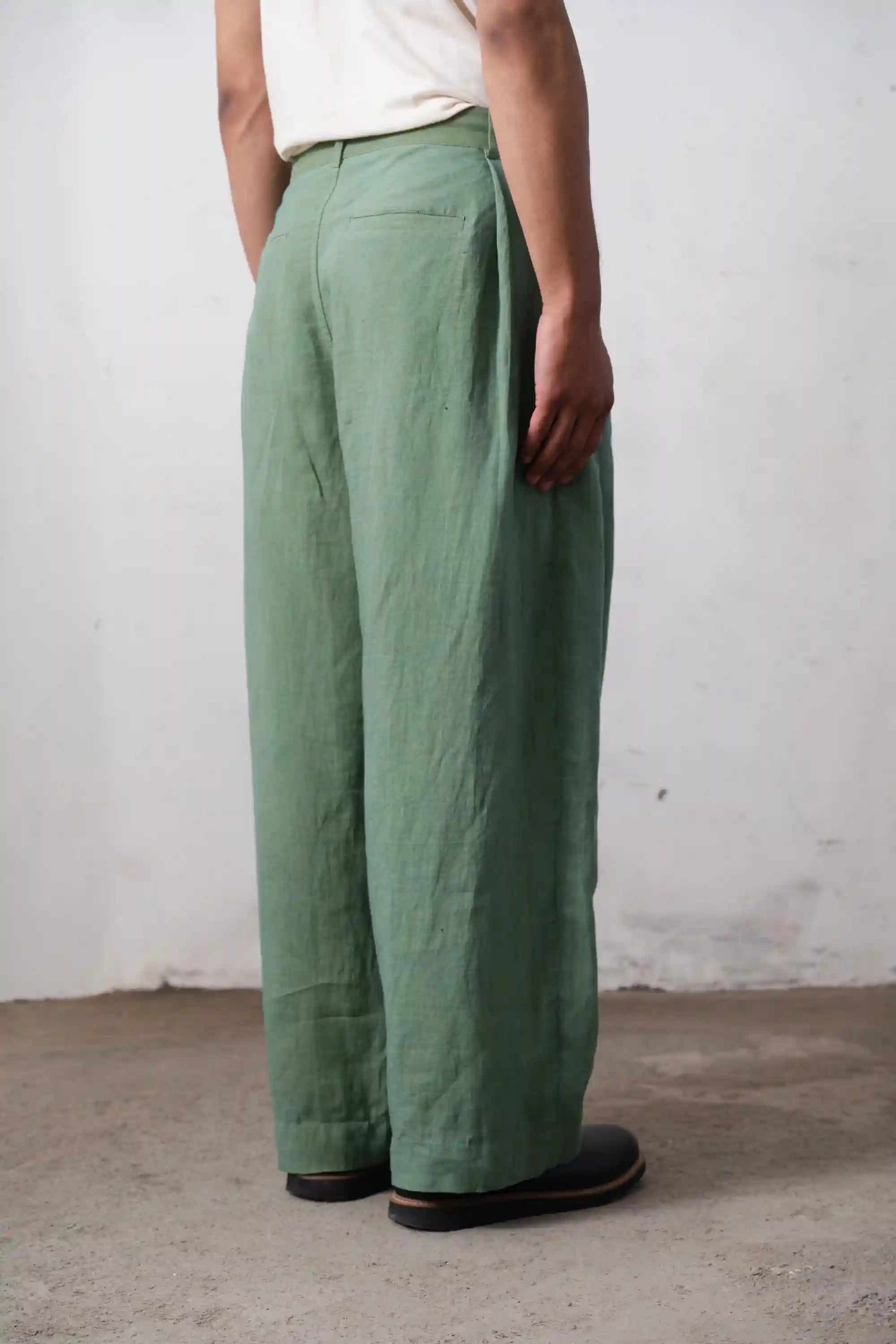 A man wearing turf green pleated pant