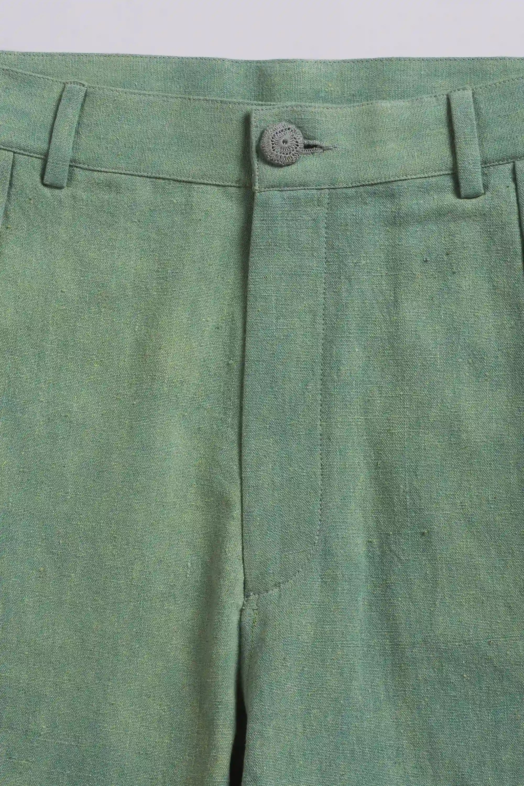 Close-up of green pants with a button on a light grey background