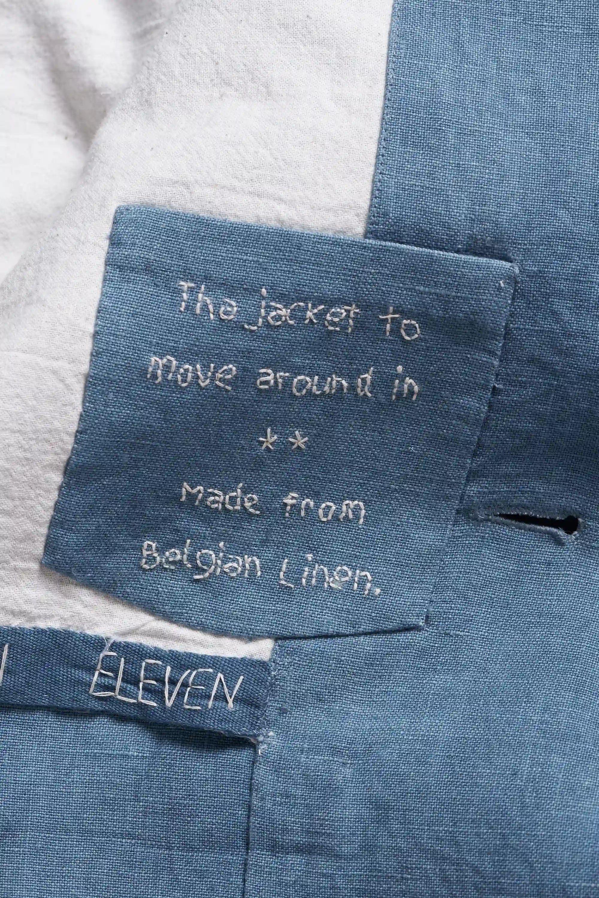 Close-up of a powder blue denim-like fabric garment with a sewn label reading