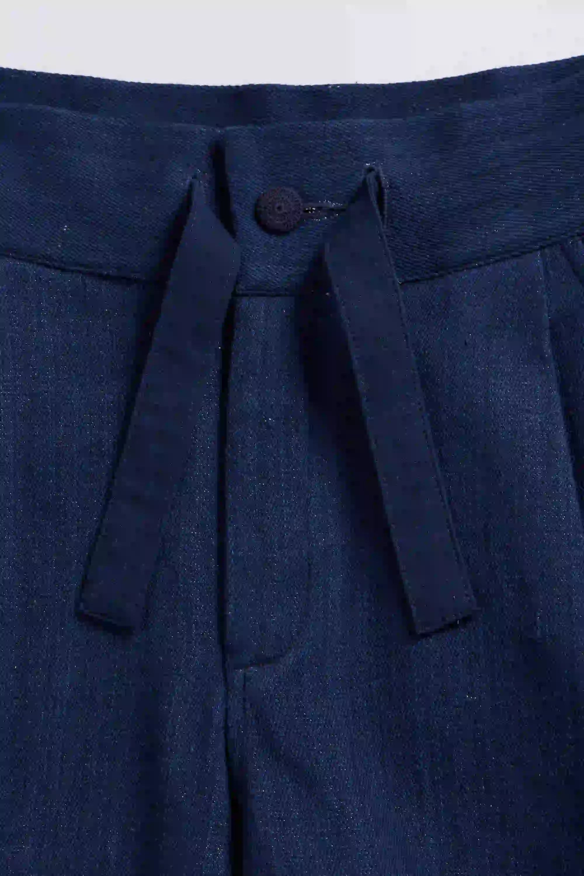 Close-up of black pants with a button on a white background