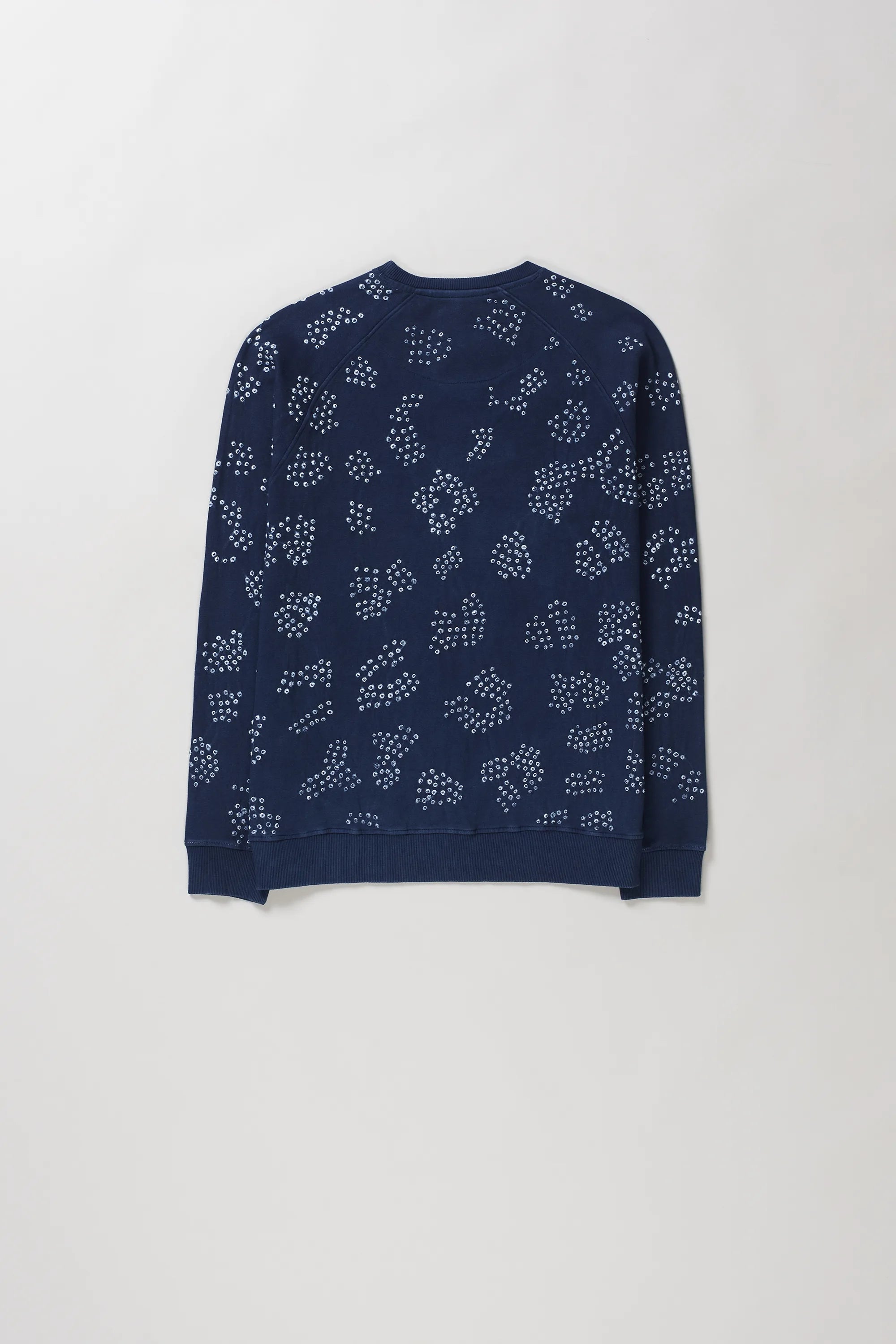 Back shot of indigo crewneck sweatshirt with an all-over white dotted abstract pattern bandhani, laid flat against a light grey background.