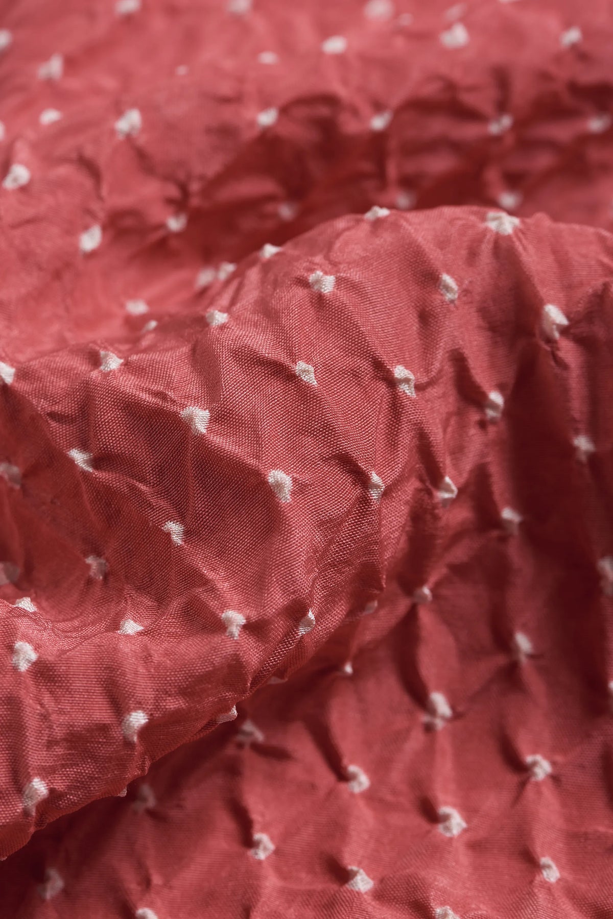 A close-up of pink wood fabric with small bandhani.