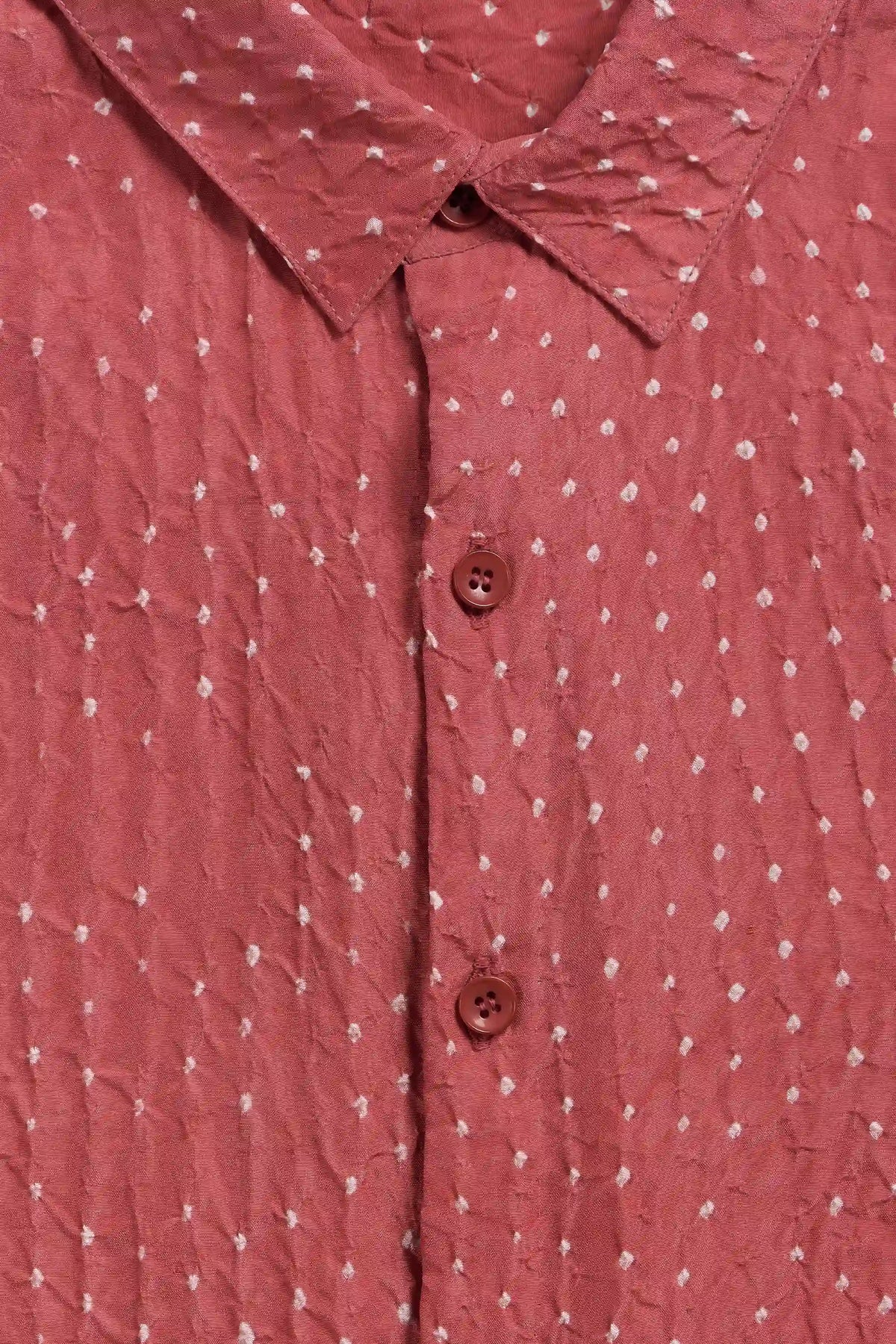 Close-up of a pink wood button-up shirt with a white dotted pattern and buttons.