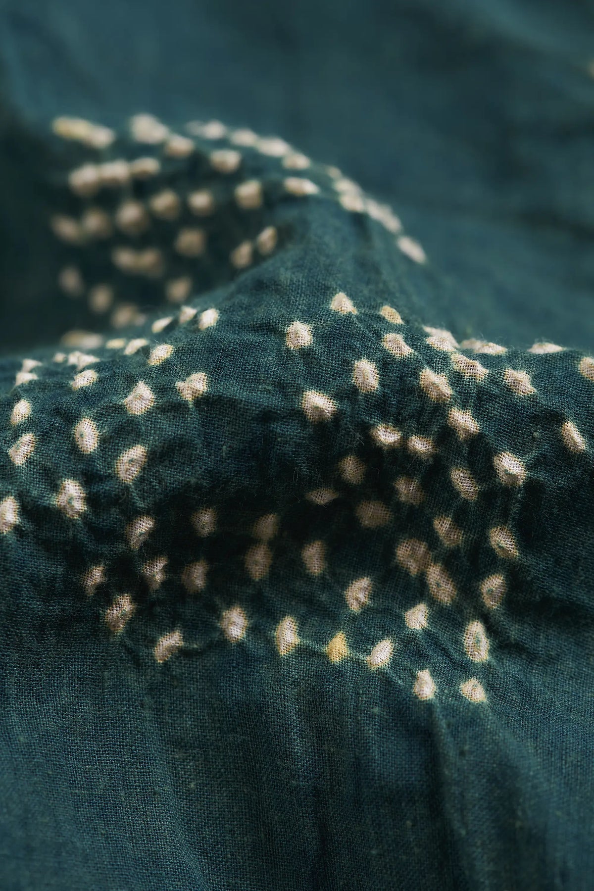 Close-up of a bottle green fabric with a bandhani dots.