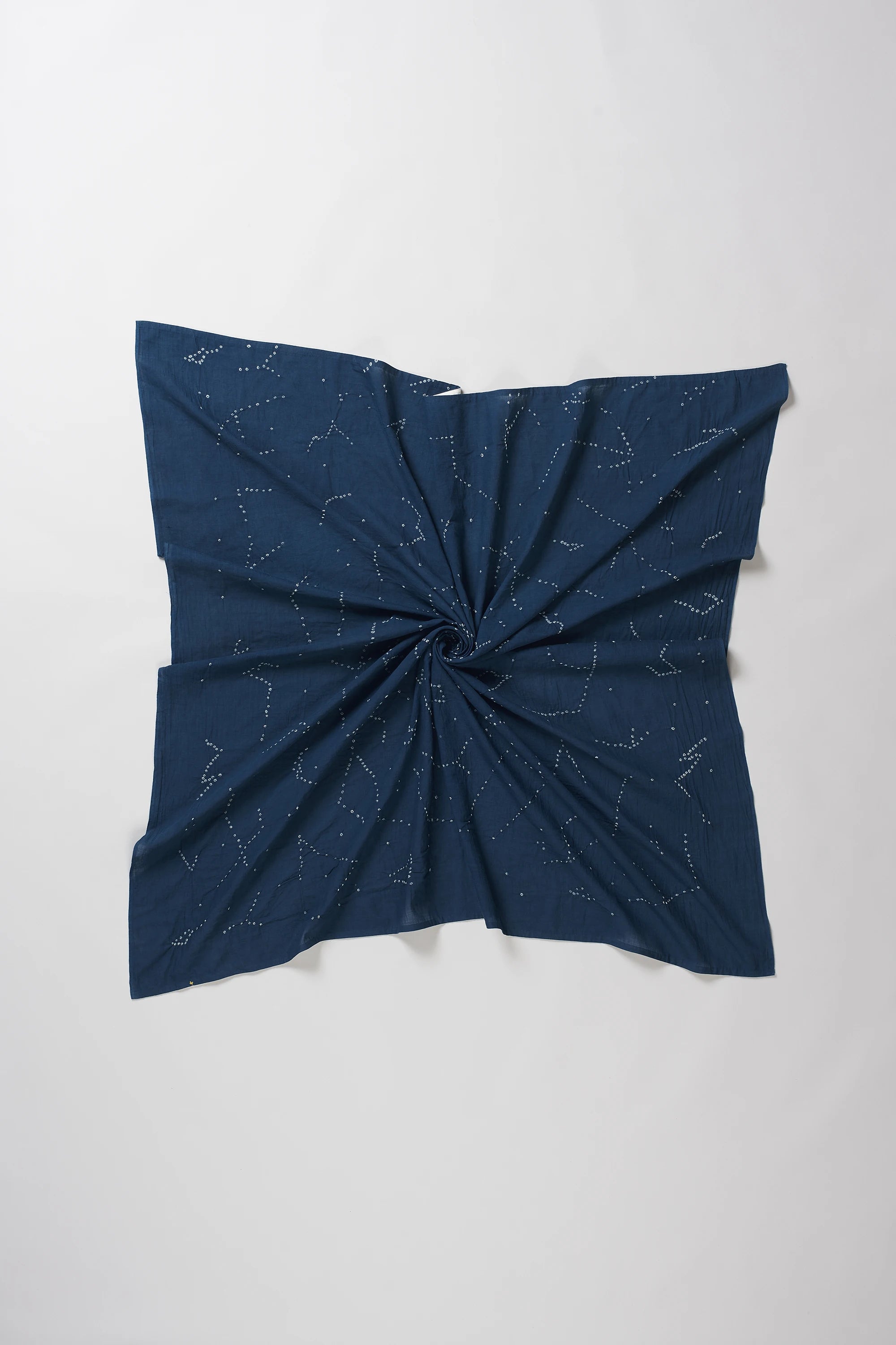 A space blue fabric scarf or bandana featuring a white constellation print, styled with a central twist on a light grey background.
