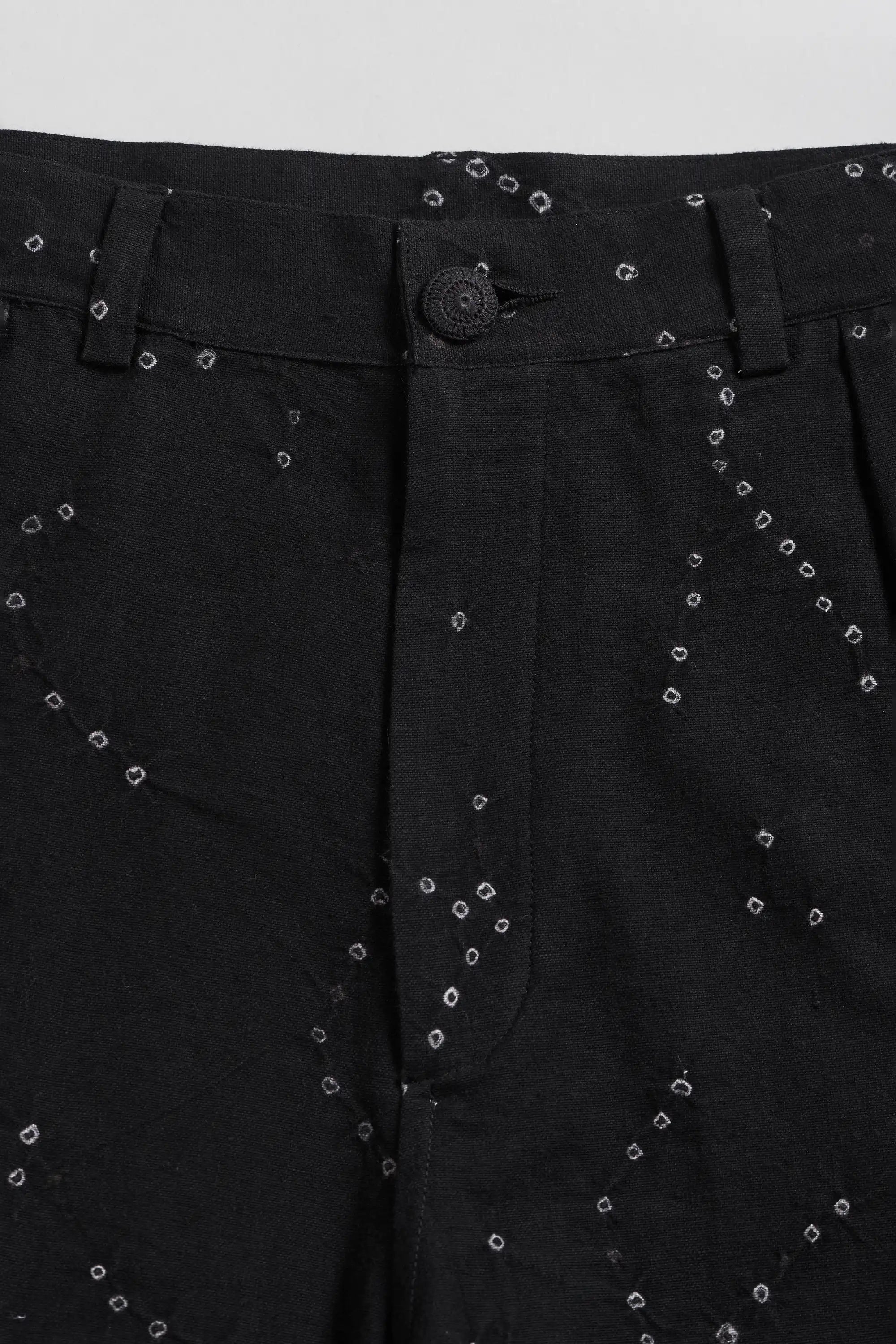 Close-up of black trousers featuring a subtle all-over bandhani.
