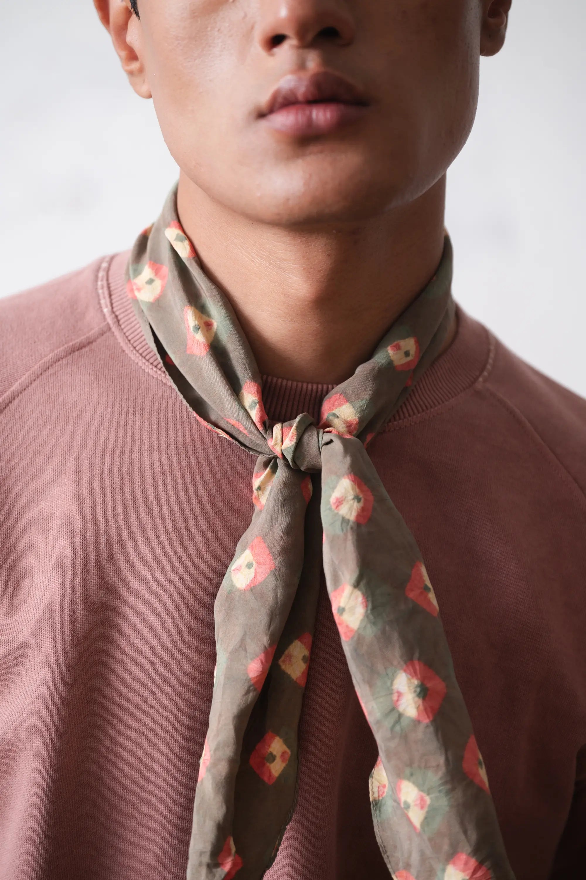 Person wearing a hand shibori scarf around their neck with sweatshirt background