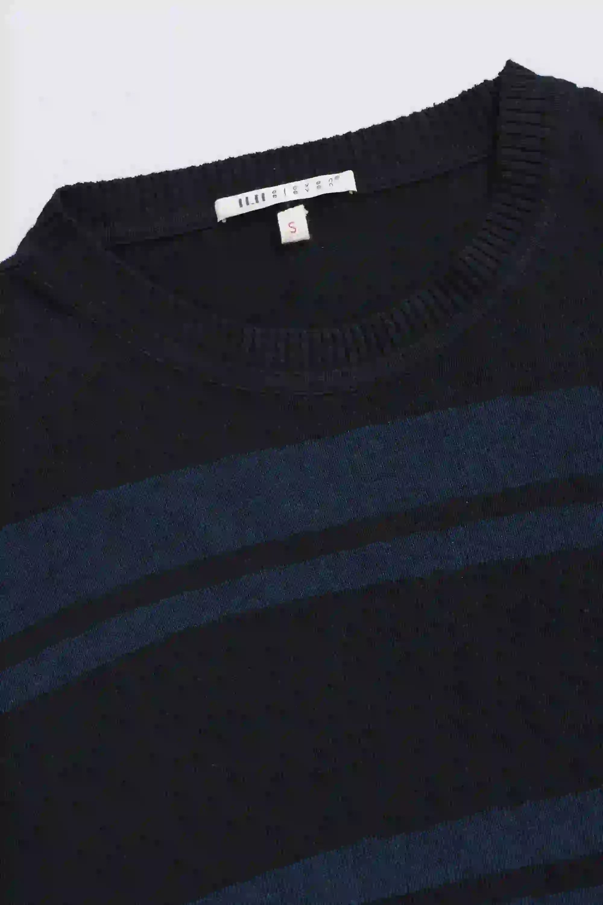 Close-up of a navy blue sweater with horizontal stripes, brand label visible.