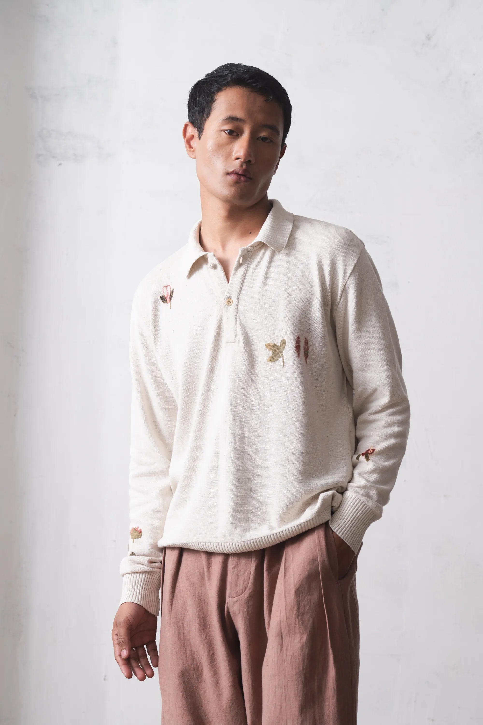 Man wearing a ecru t-shirt and standing against a light grey background