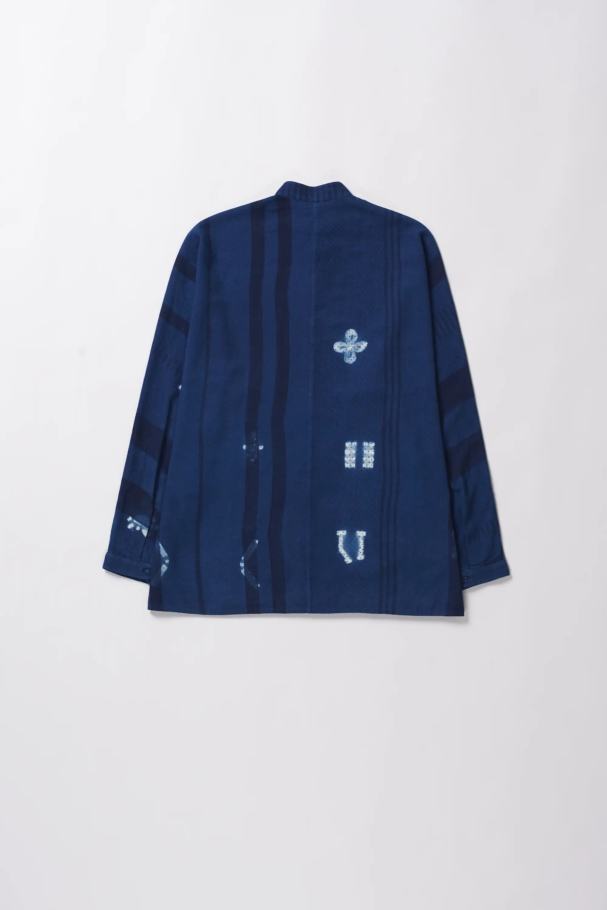 Back shot of indigo shirt with white shibori patterns on a grey background