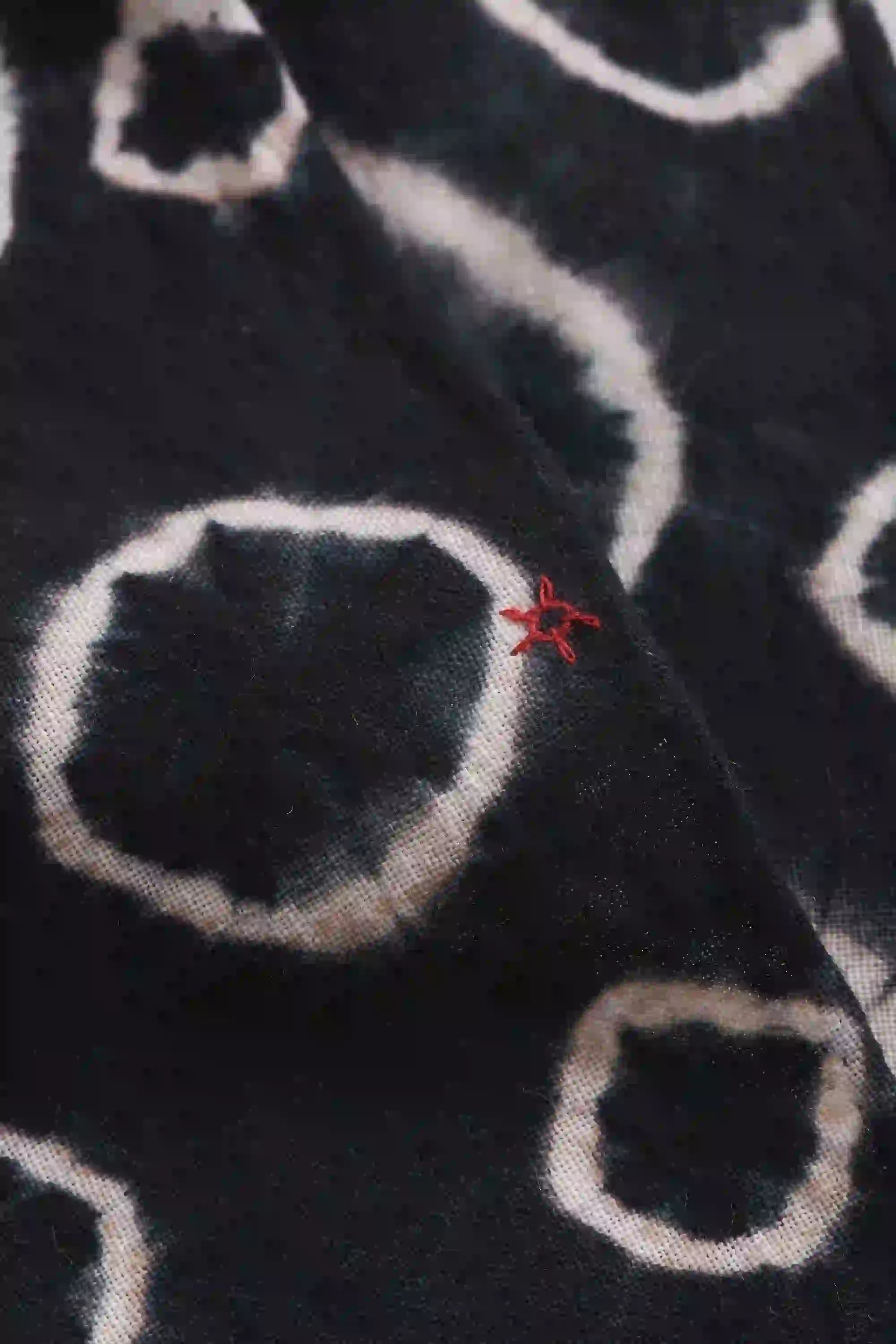 Close-up of black fabric with white circular patterns and a red star-like design.