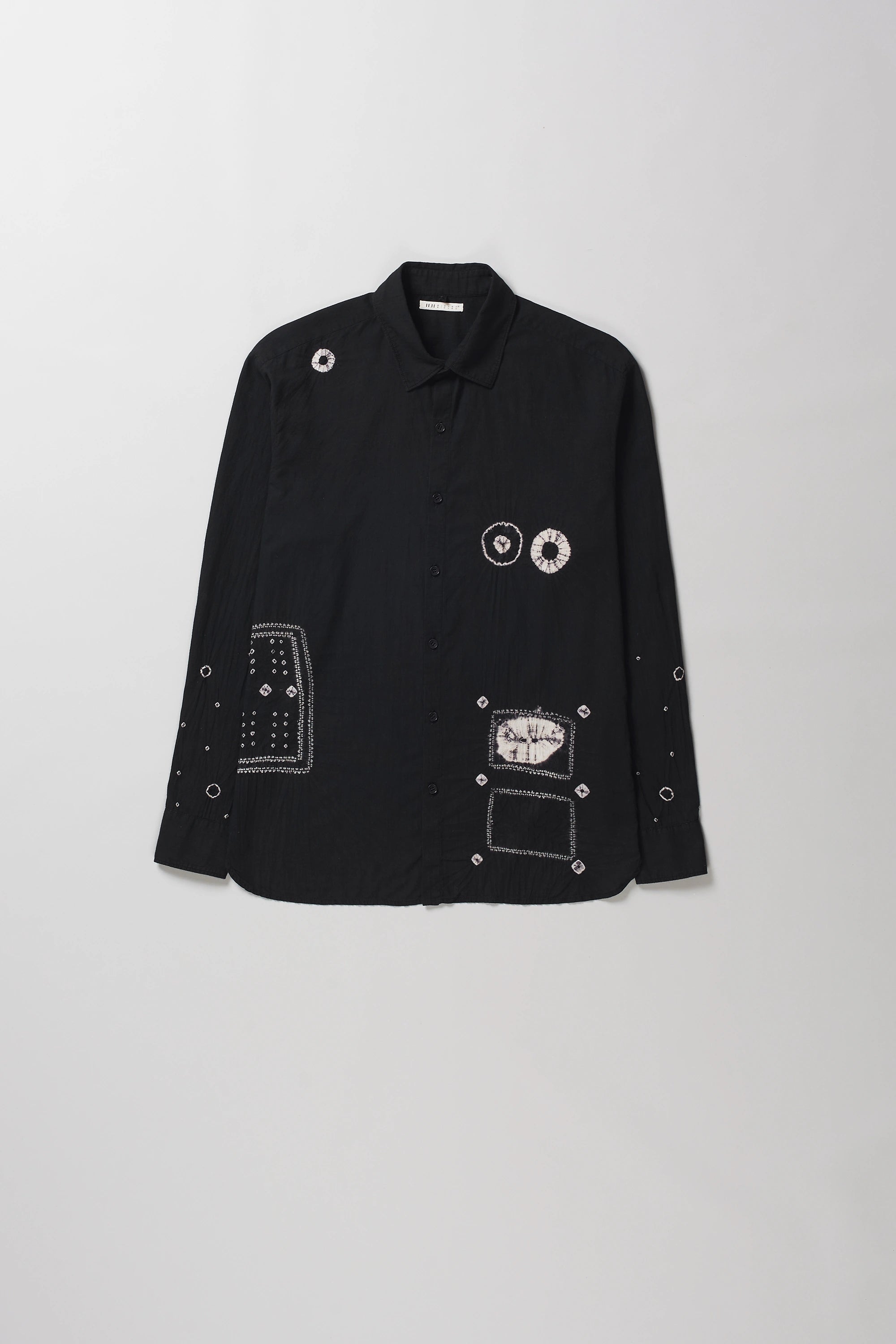 A black long-sleeve button-up shirt with shibori details, displayed flat against a light gray background.
